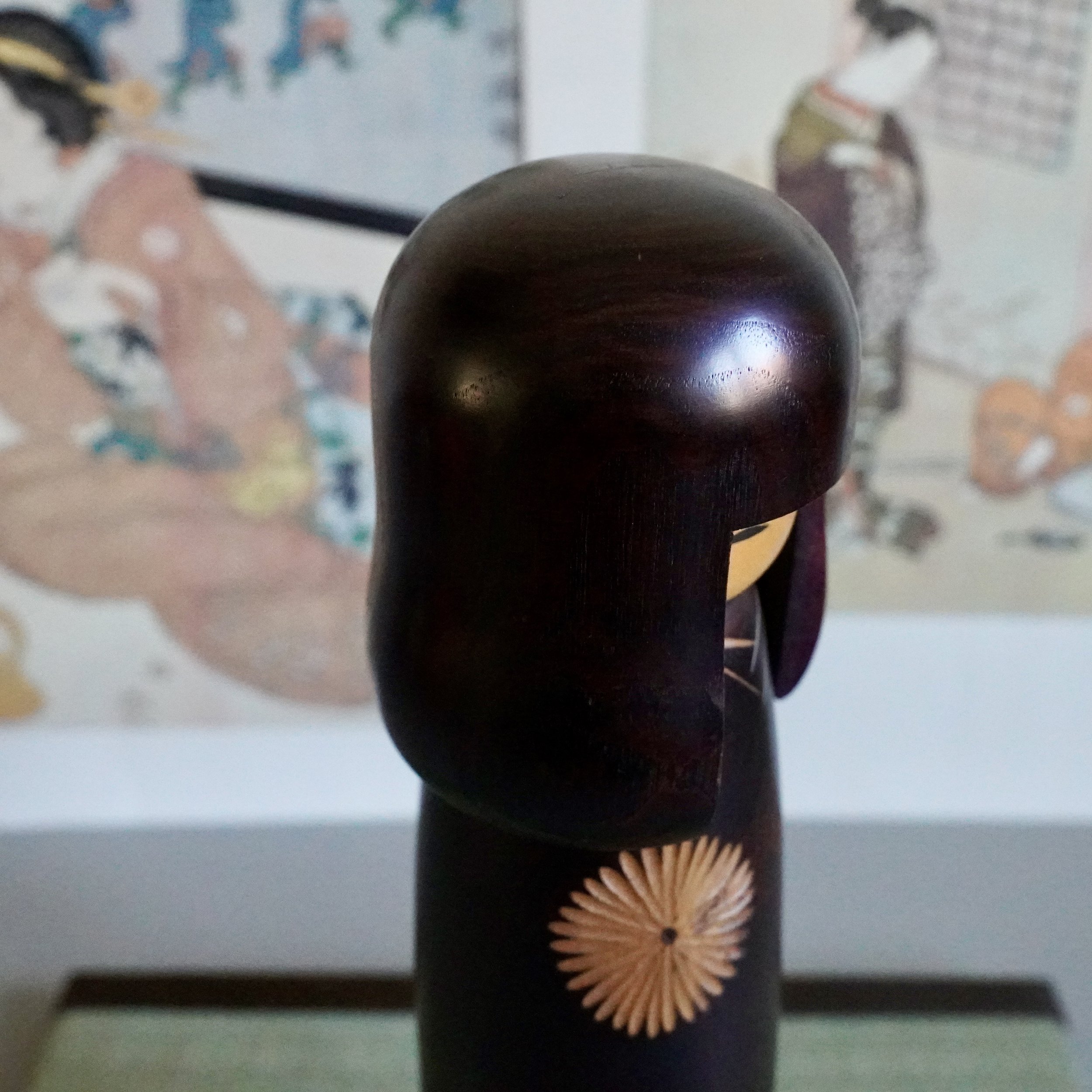 Sosaku kokeshi head side view, carved fringe detail, asymmetric hair panels, dark stained wood