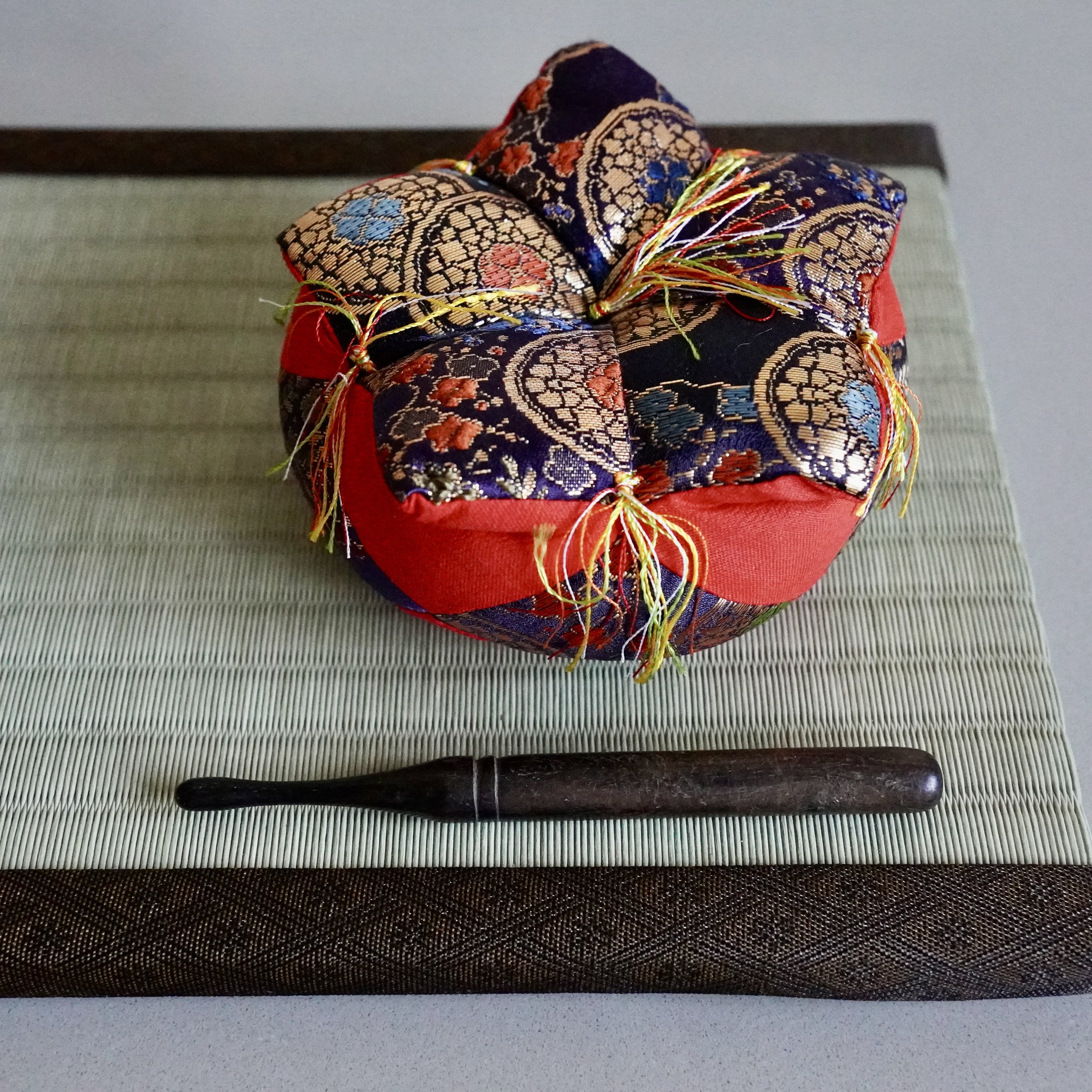 Red and purple brocade cushion with striker for Japanese orin singing bowl, tatami mat