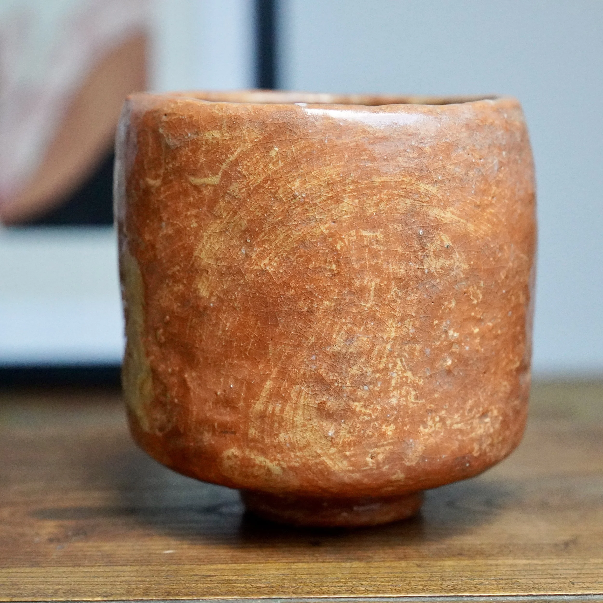 Tall, terracotta-toned ceramic bowl from Hioki Nanshū kiln, with a crackled glaze, cream brushstrokes, and a white drip glaze from the rim, on wood.