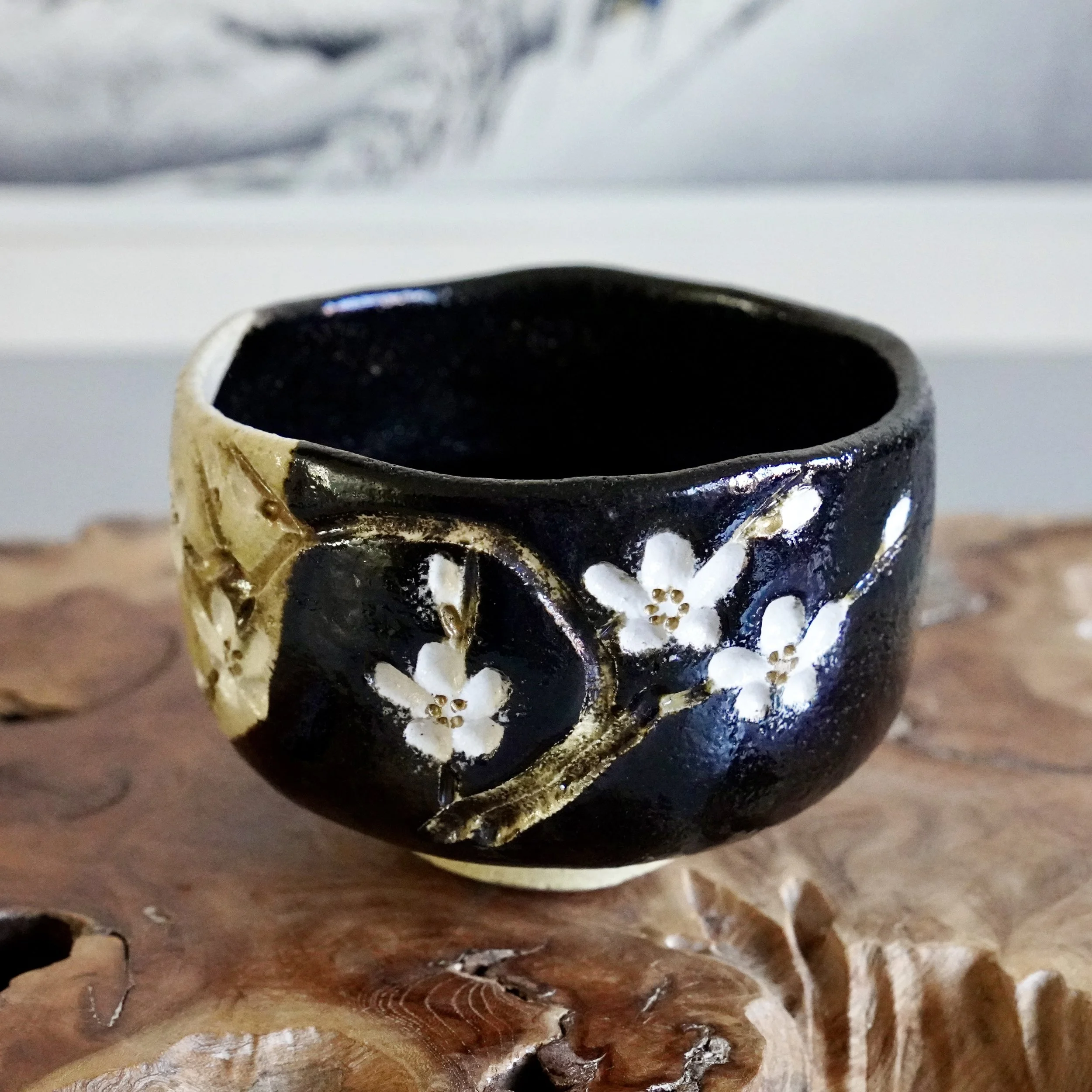 Curved cherry blossom branch detail on black glazed chawan rim