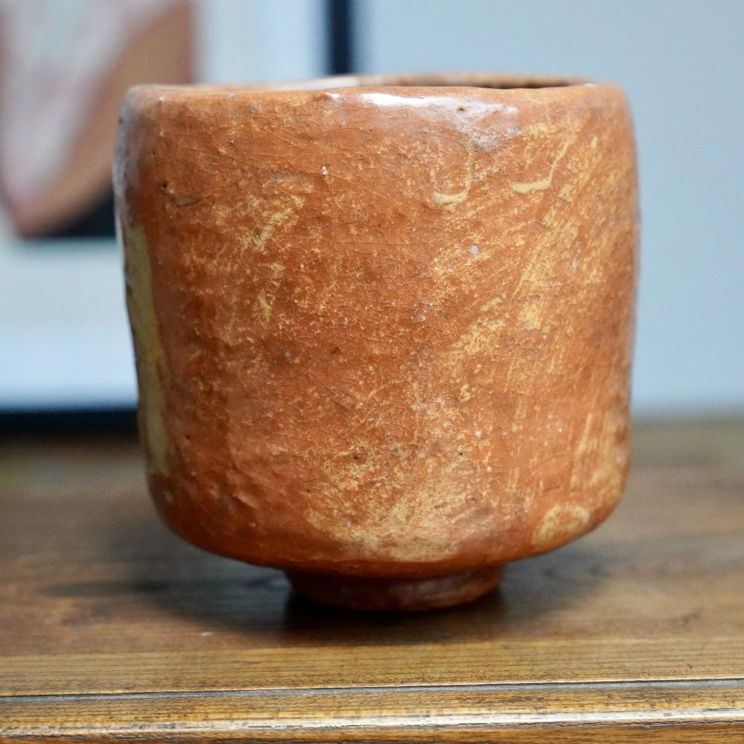 Tall, straight-sided chawan by Hioki Nanshū kiln, terracotta-colored with a crackled surface and cream accents. A white glaze drips from the rim and fades halfway down one side.
