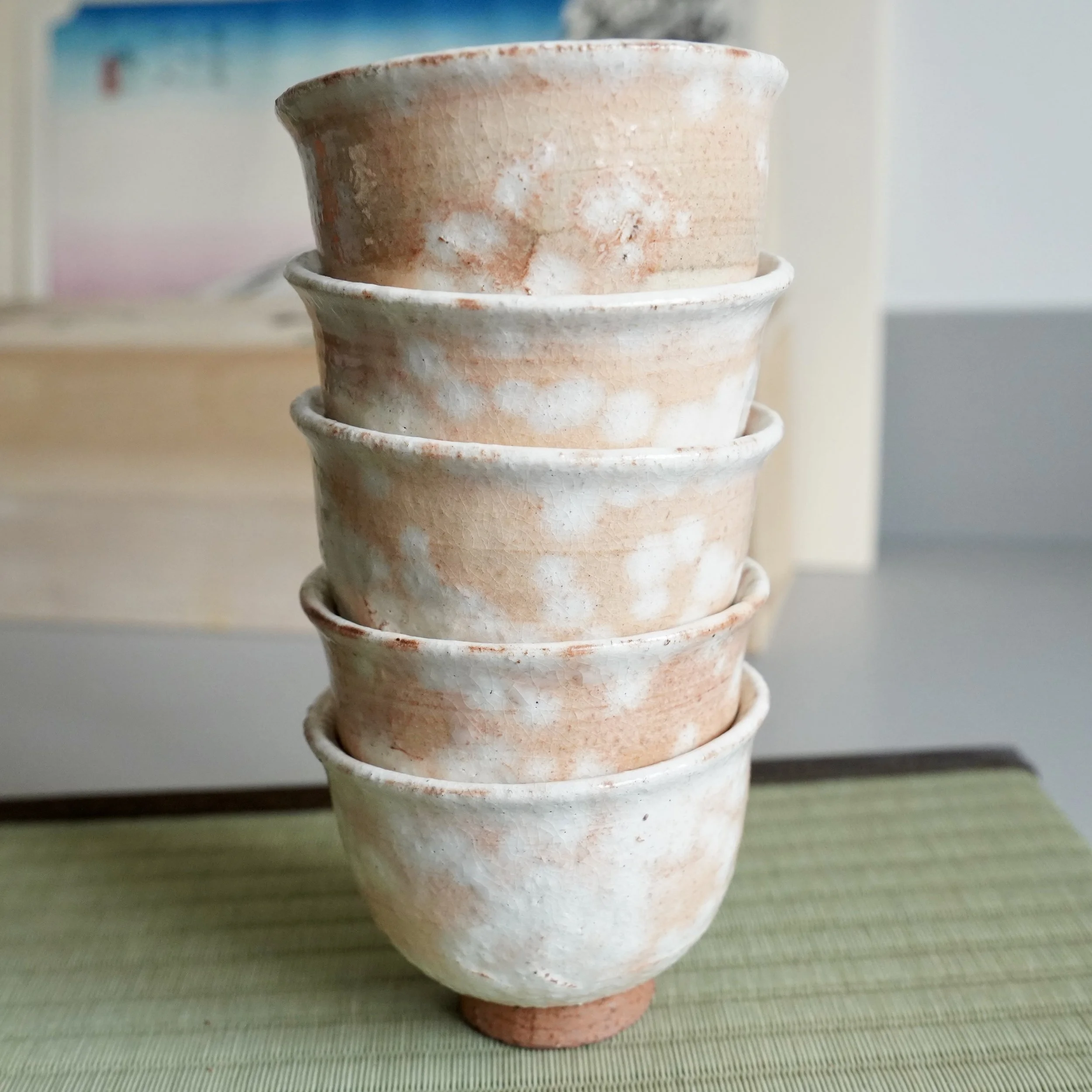 Stack of five shira-hagi yunomi by Taizan kiln 泰山窯 Hagi-yaki, front view showing scale and complete set, warm white glaze with russet cloud markings, Japan Shōwa period