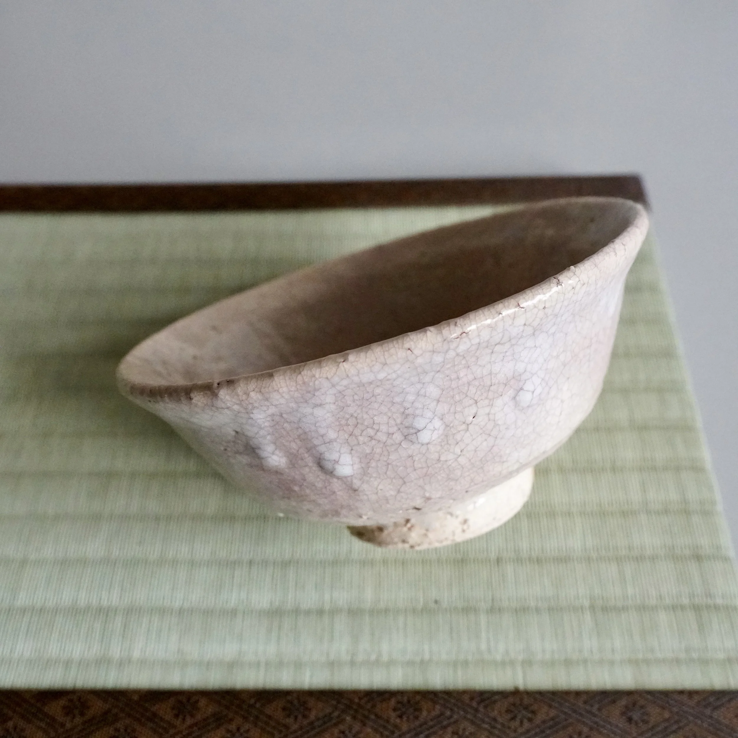 Hagi ware summer chawan side view showing gently irregular kutsugata rim and pale crackled glaze