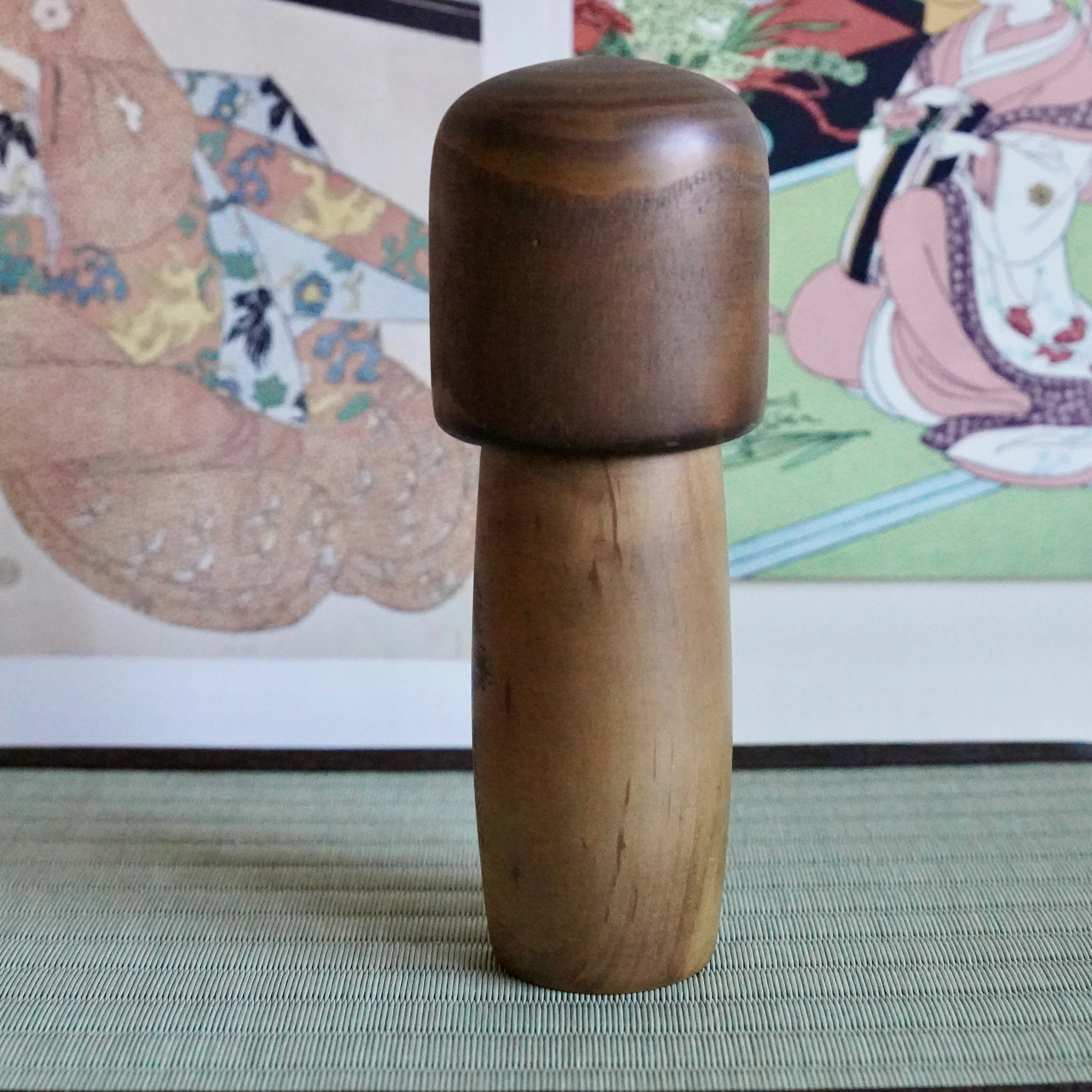 Side view of vintage Usaburō kokeshi doll, dark wooden bob and honey wood body