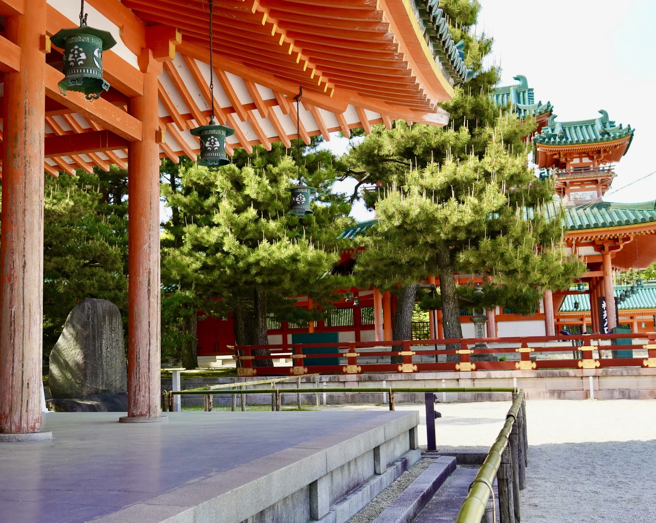 Heian Shrine covered corridor in Kyoto with pine trees and hanging bronze lanterns, an example of considered space in Japanese temple architecture