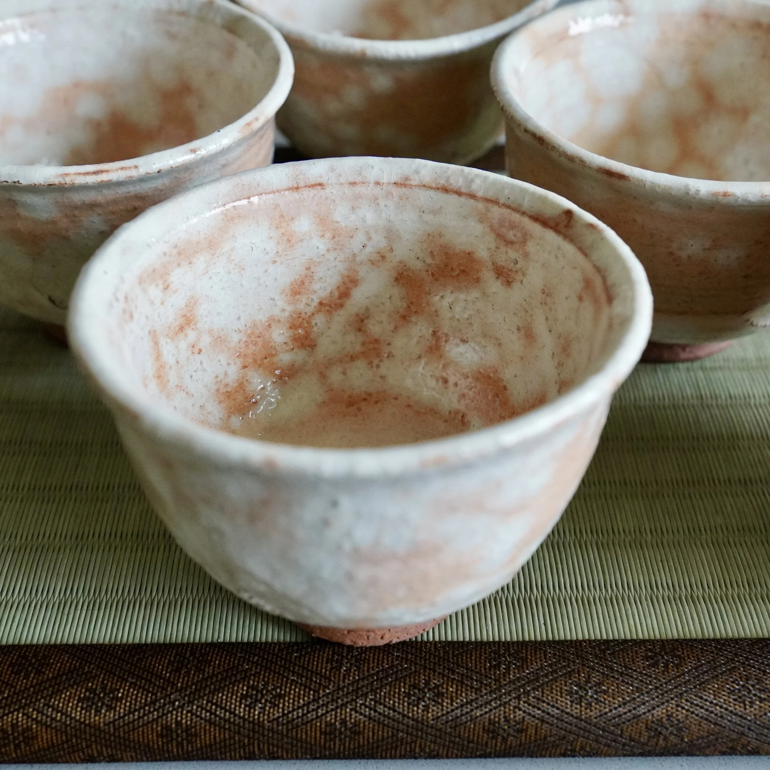 Shira-hagi Hagi-yaki yunomi by Taizan kiln, three-quarter angle showing glaze variation from pooled white to warm terracotta, fine kannyu crazing, Japan Shōwa period