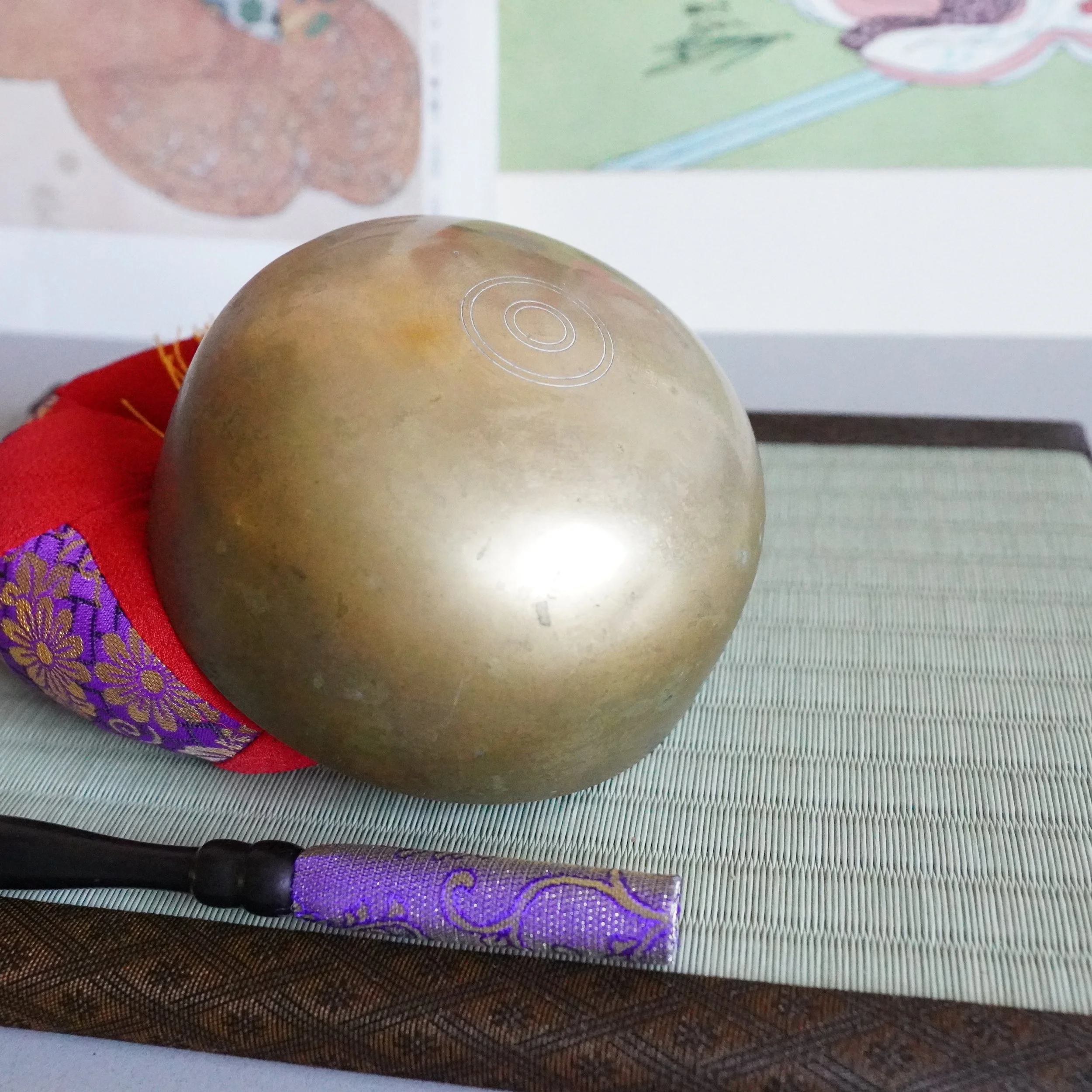Underside of bronze orin bowl on brocade cushion, tatami mat