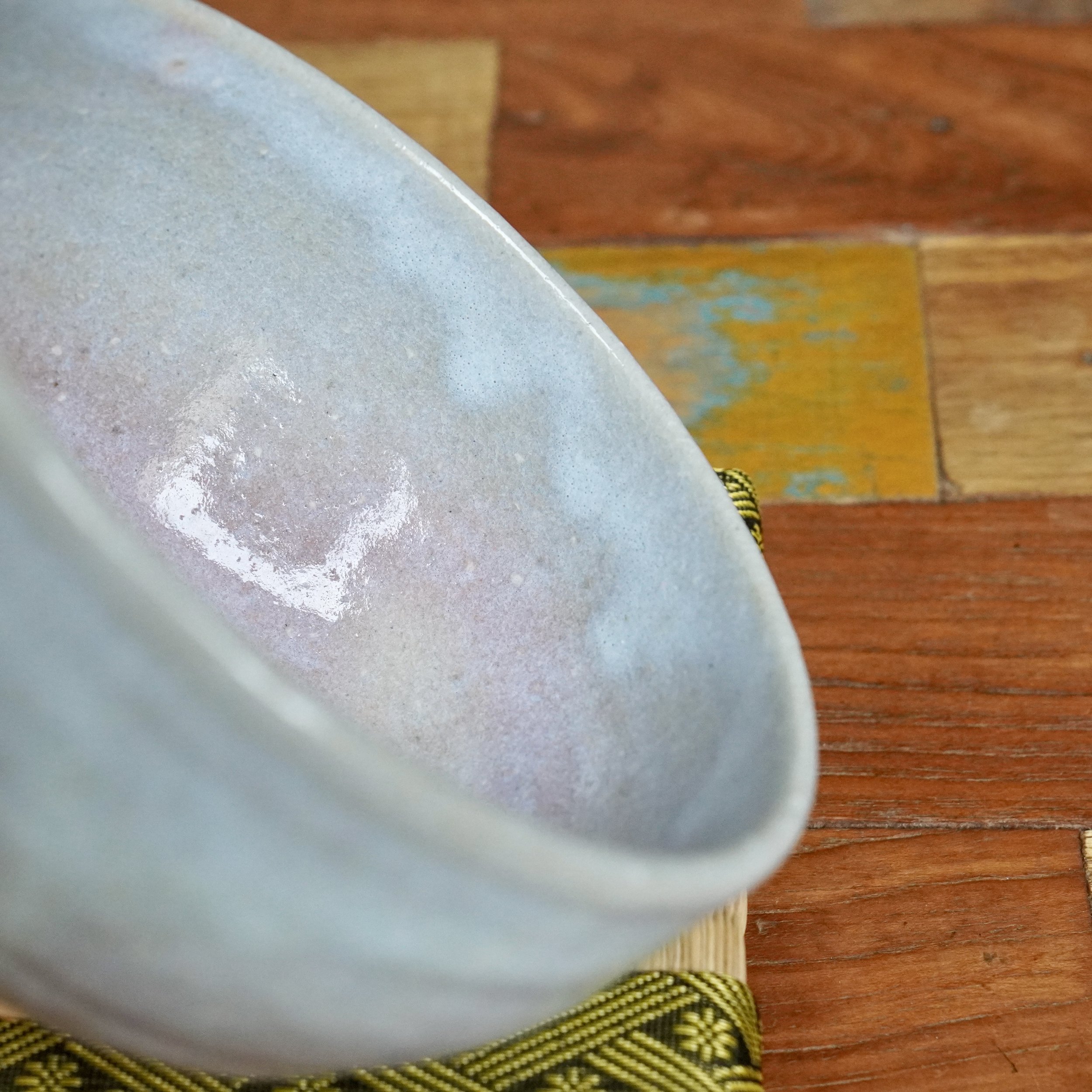 Close-up of Moriwaki Fumitada's Hagi-yaki chawan, showing its interior with a glossy, light blue-grey and lilac glaze and subtle speckles.