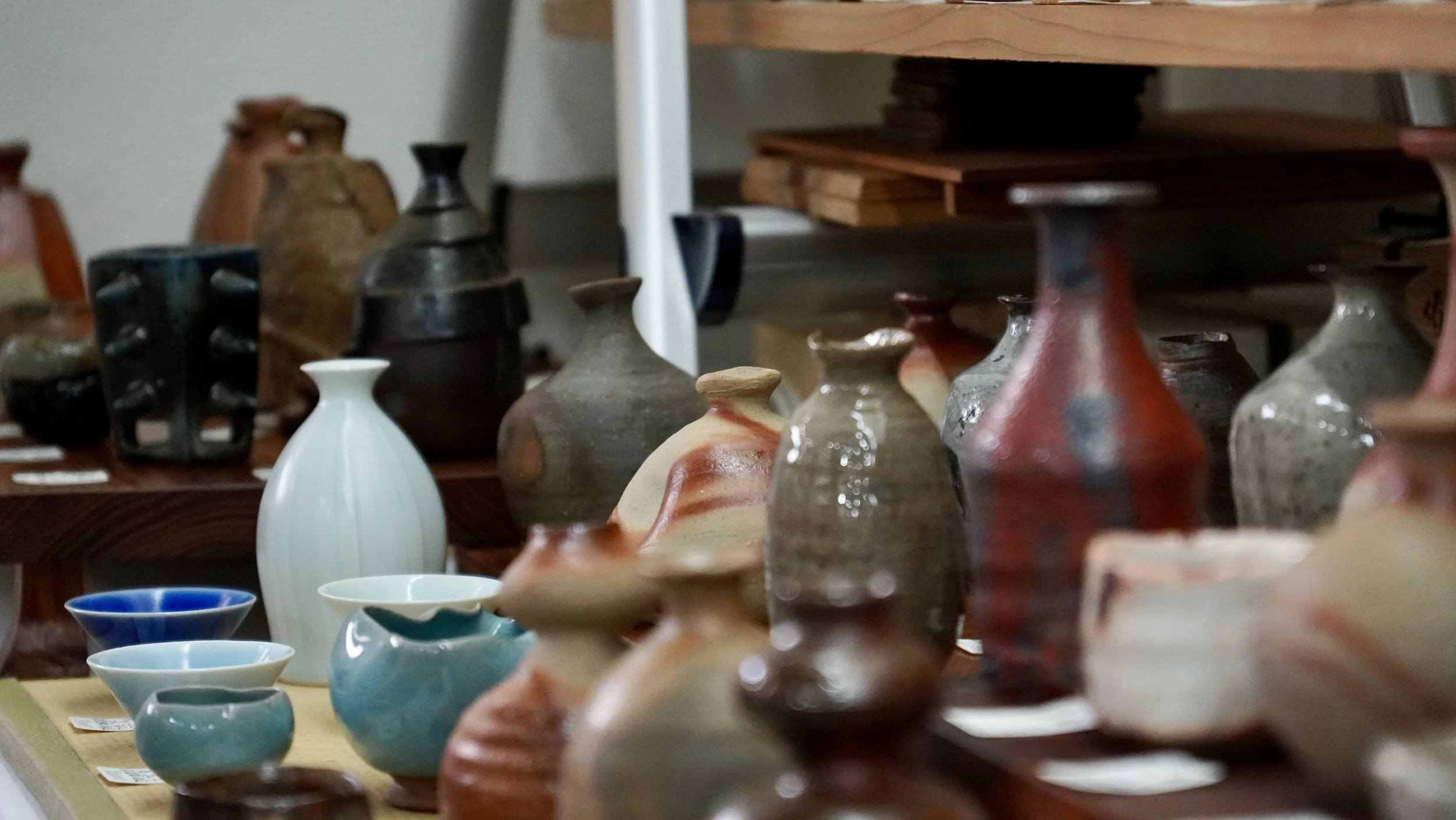 Wide variety of Bizen-yaki ceramics at Japanese pottery exhibition in Imbe Okayama, showing multiple yohen kiln effects including hidasuki sangiri goma and hiiro in one display