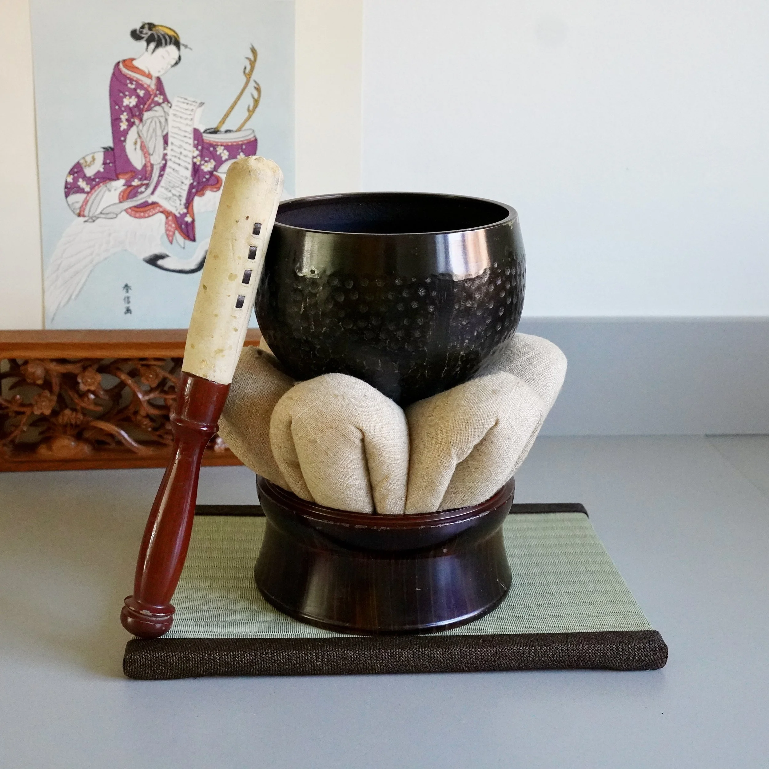 A large vintage bronze orin singing bowl set from Kyoto with a hammered tsuchime finish, resting on a traditional cushion and wooden stand with a striking mallet.