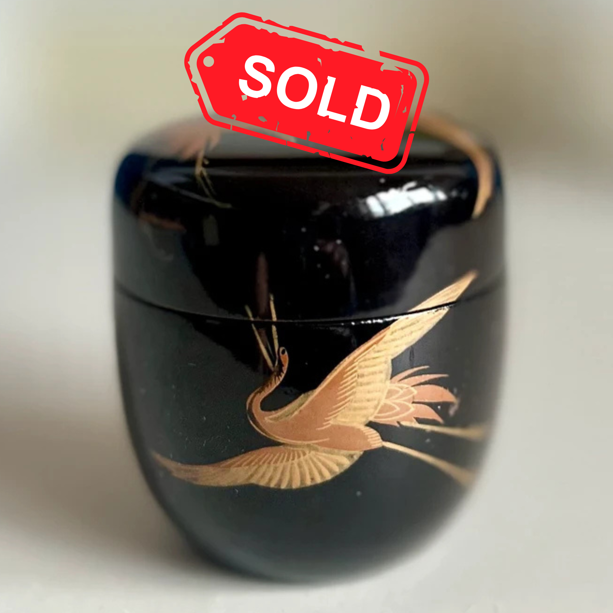Urushi lacquerware natsume black with maki-e gold crane decoration, Shōwa period Japan on white background showing the shine of the lacquer and gold