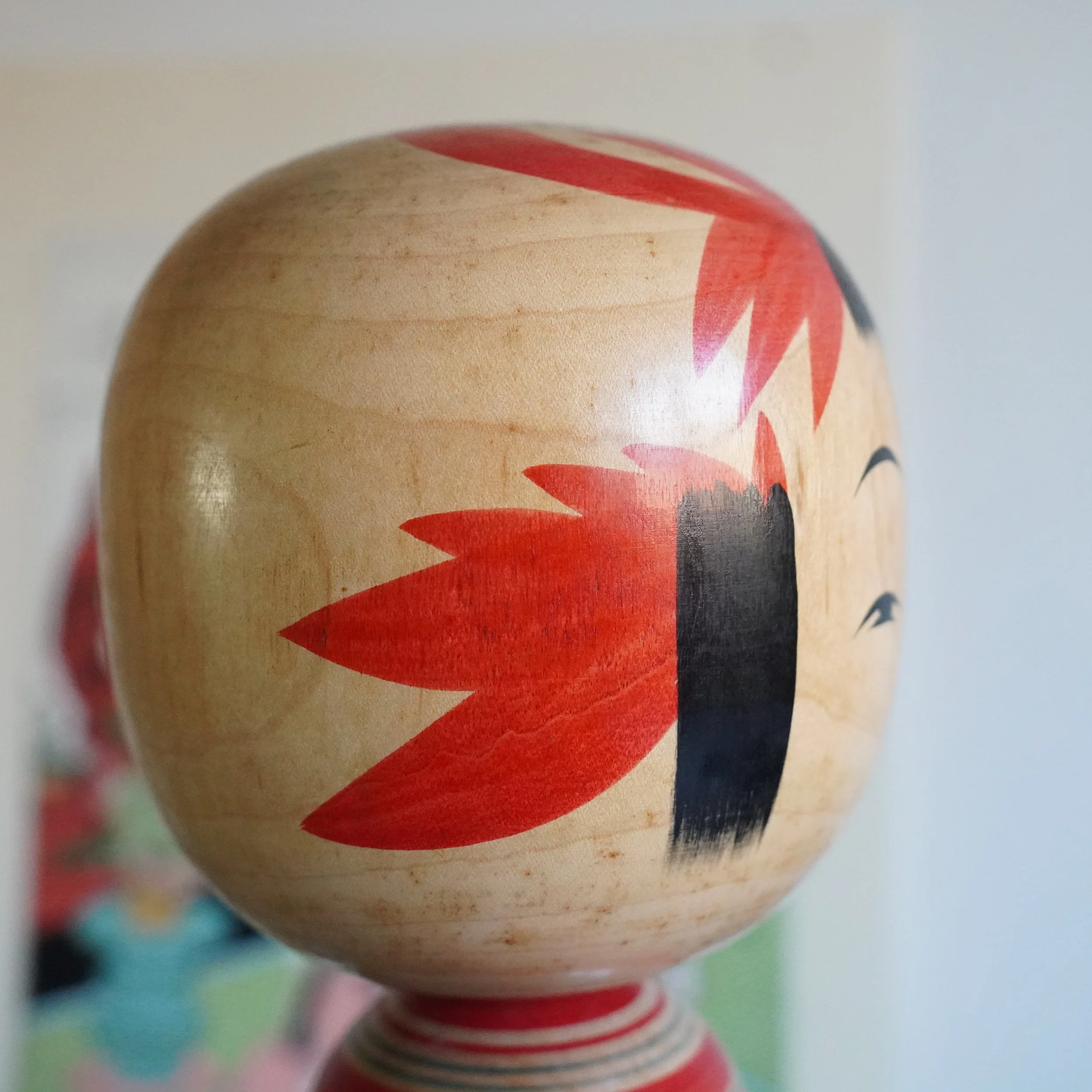 Top view of Yamagata kokeshi head by Takasaki Eiichirō, red painted floral decoration on crown, smooth natural wood, overhead shot showing painted motif pattern, Shōwa period