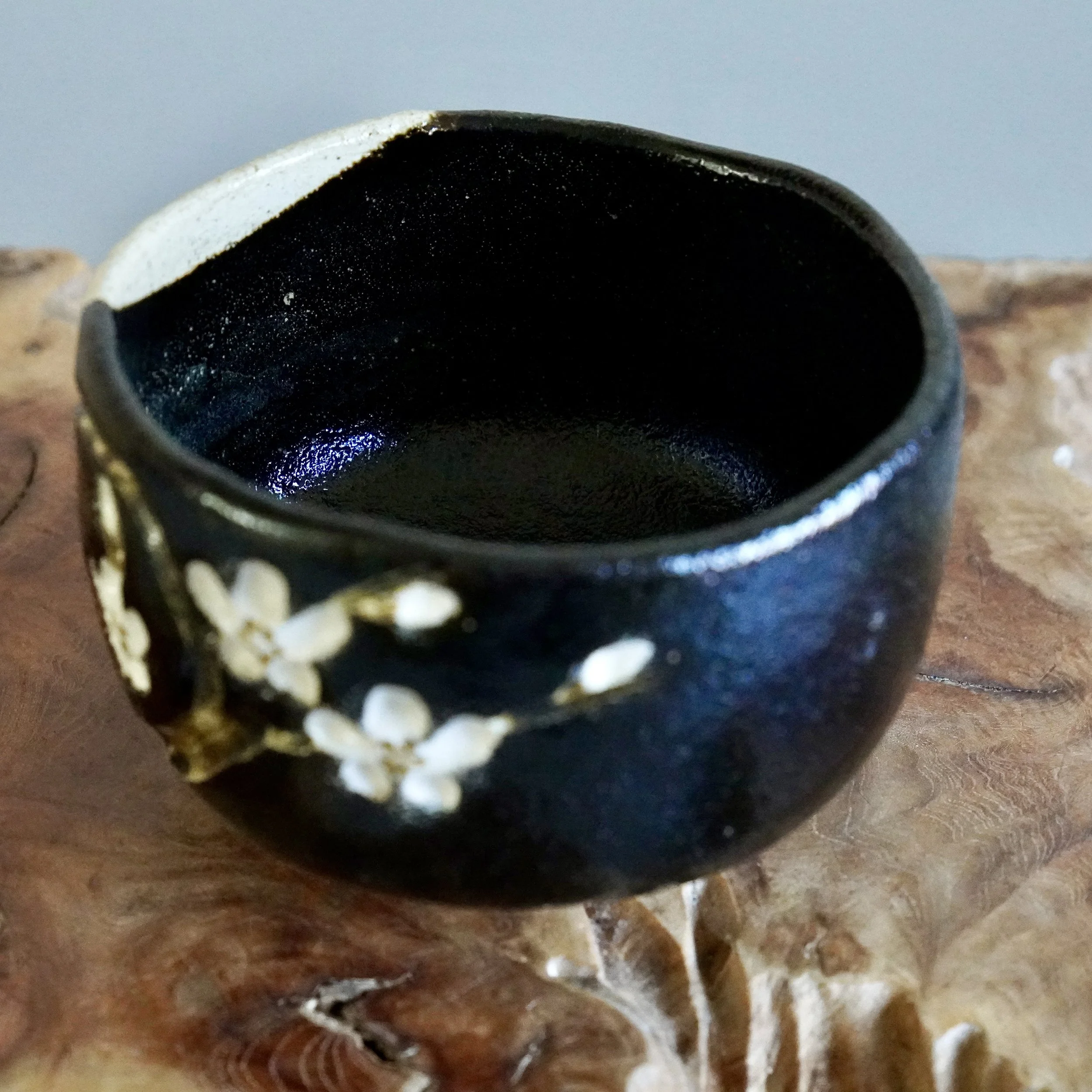 Close view of carved cherry blossom motif on kuro chawan