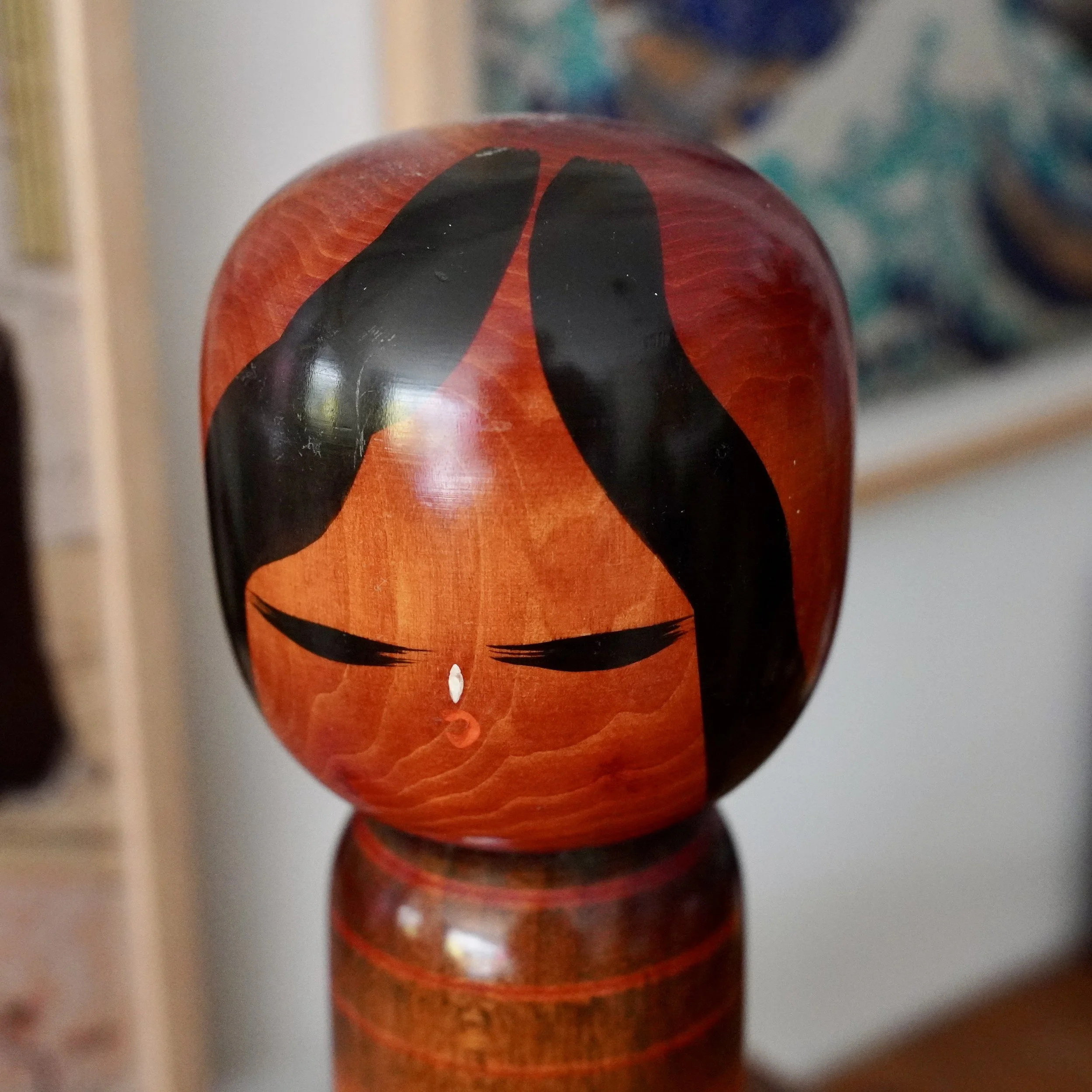 Front view of camellia girl kokeshi face, painted eyes and teardrop