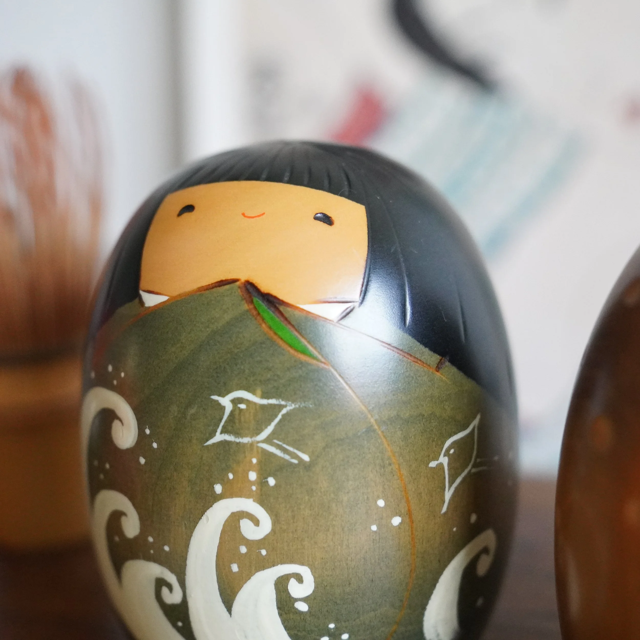 Close up of vintage Usaburo kokeshi summer doll, hand painted wave motif and face, Showa period Gunma Prefecture