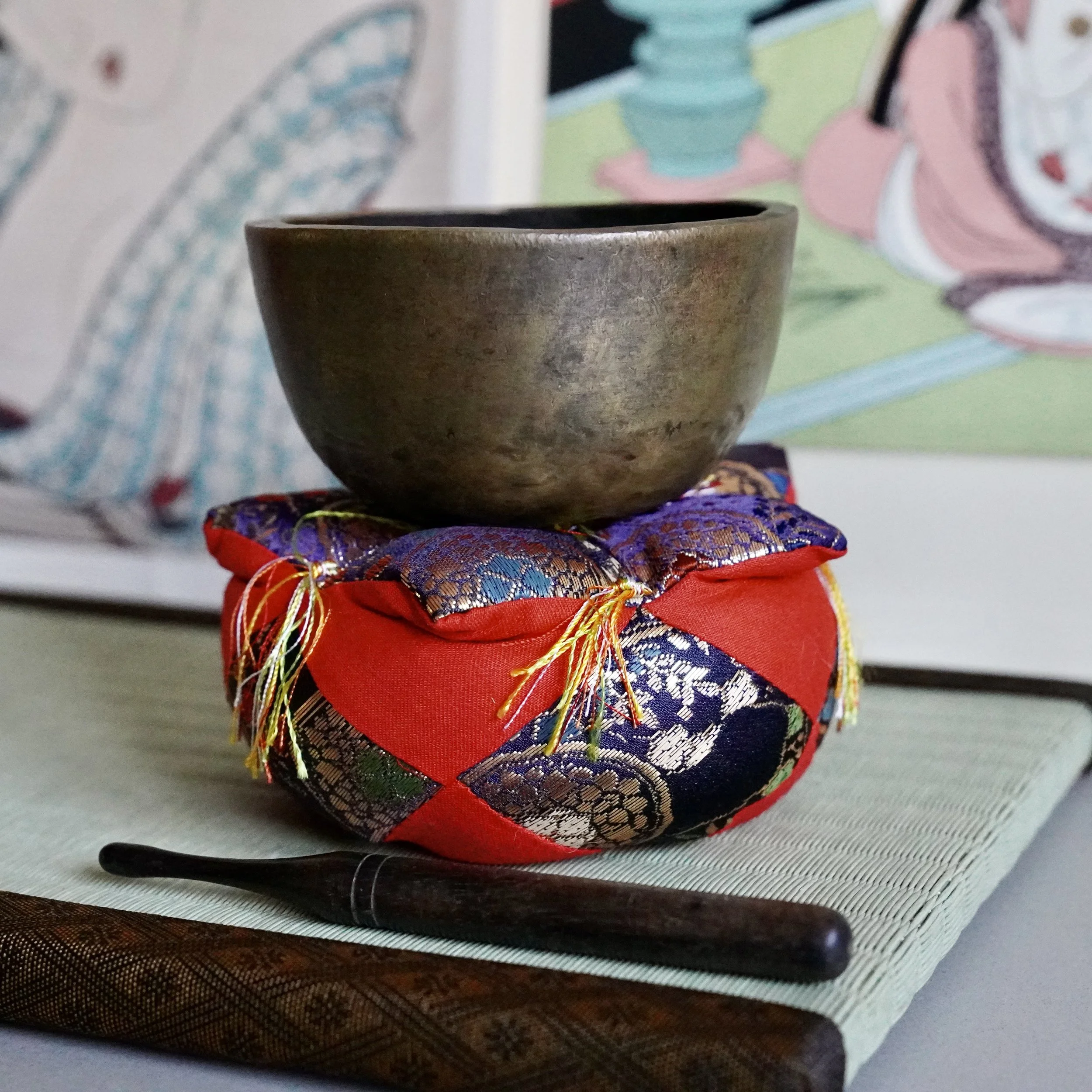 Front view of small hand-hammered bronze orin singing bowl on brocade cushion