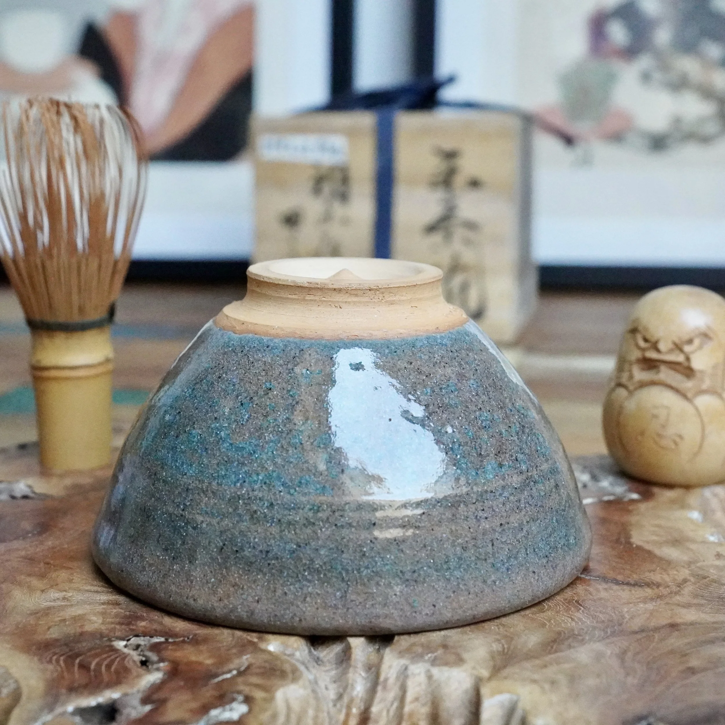 Mizushima Jirō's Kagurao-yaki chawan, inverted, with speckled blue and grey glaze, and an unglazed tan foot with a raised conical point, on wood.