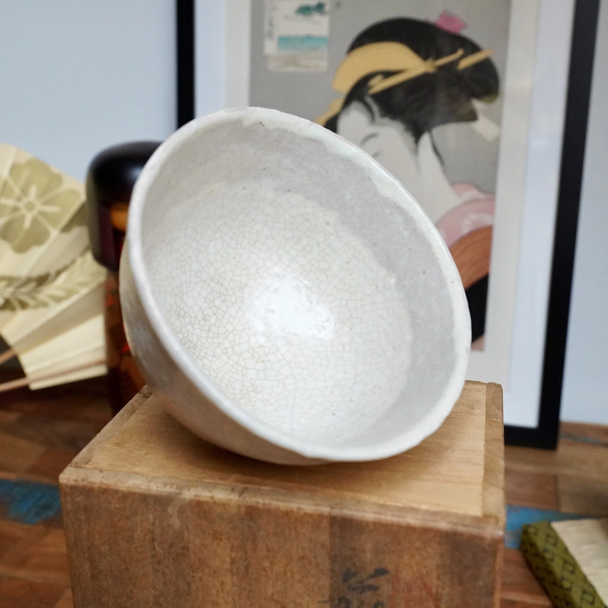 Hagi-yaki chawan by Tamamura Shōgetsu, tilted, revealing white crackle glaze interior with subtle tea stains. On wooden box.
