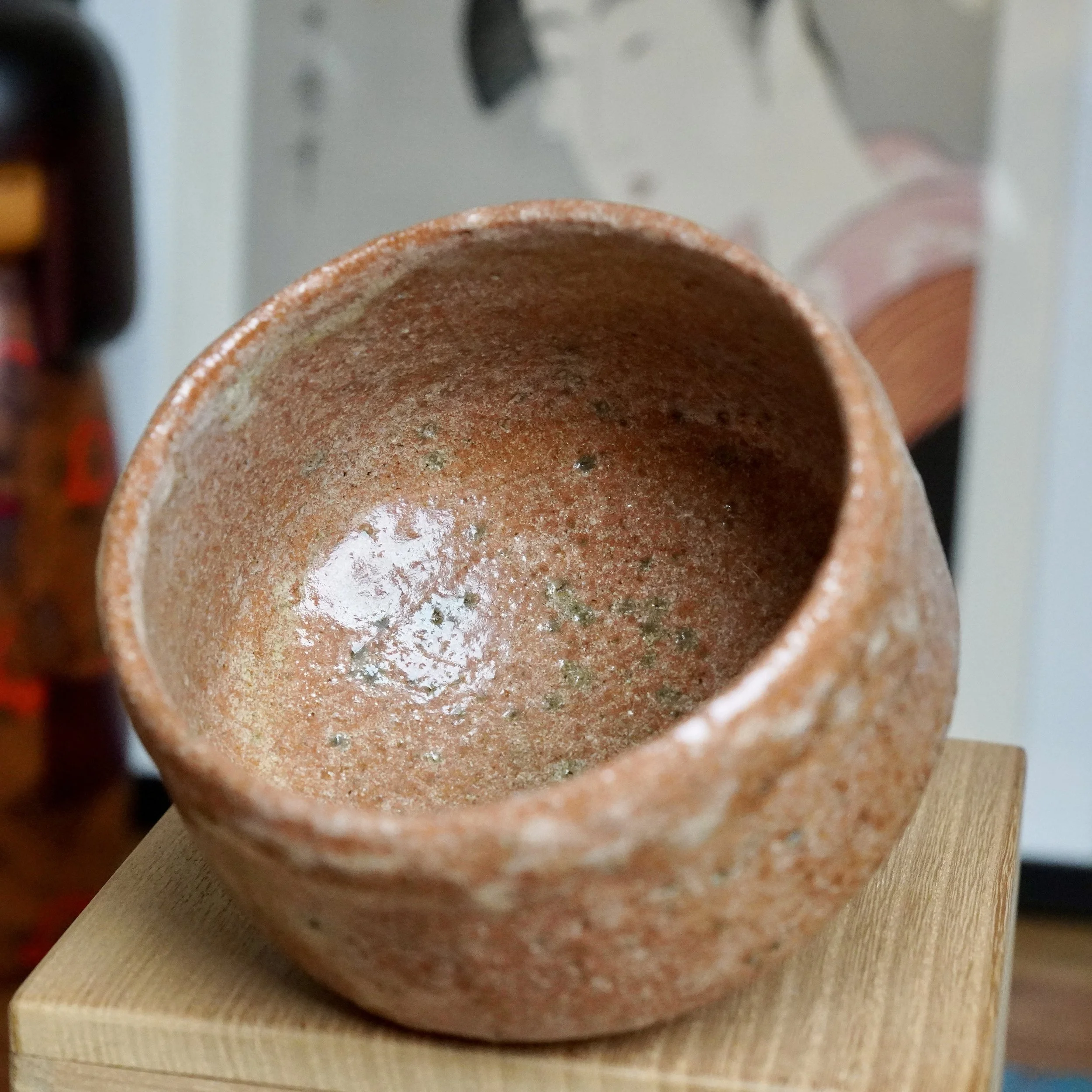 Sawada Hiroyuki's aka-raku chawan, a reddish-brown bowl with a rugged surface, glossy patches, and a distinct pale white glaze drip.