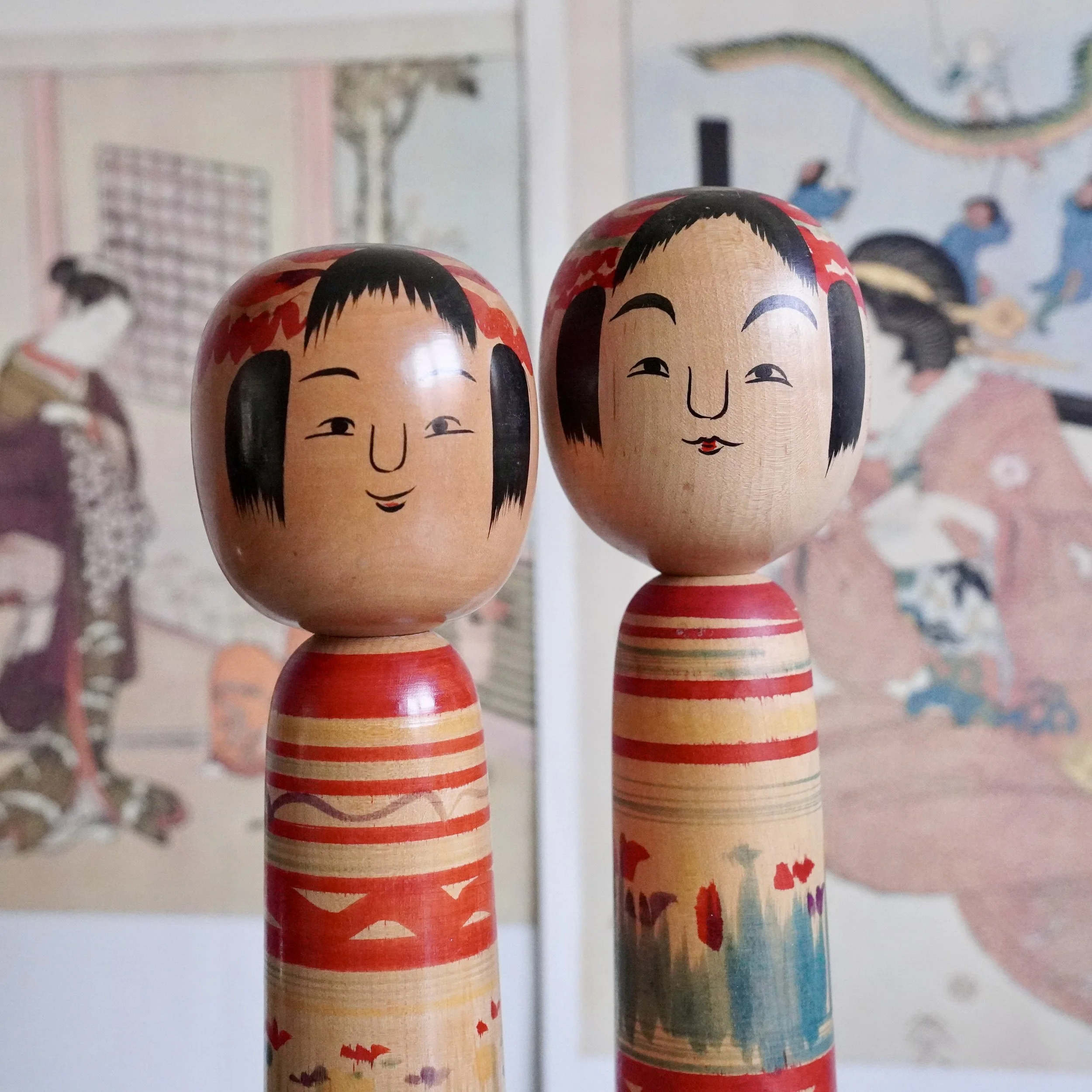 Close-up of two vintage Tsuchiyu  Kumematsu style kokeshi doll faces, one laughing open mouthed, the other with a small pursed mouth, hand painted by Jinnohara Kazunori, Fukushima Japan.