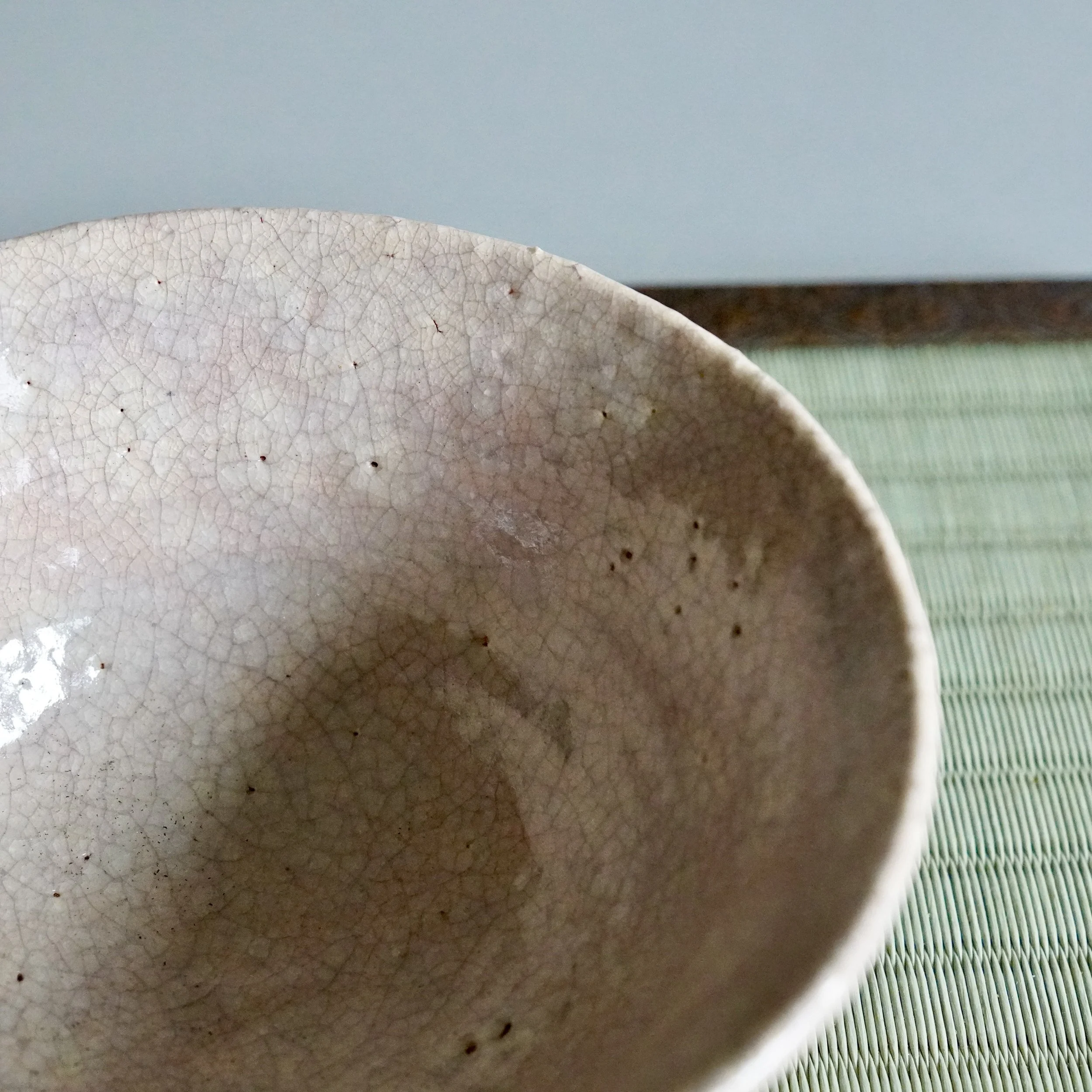 Close-up of Hagi-yaki glaze crackle inside chawan, fine kan'nyū network catching the light