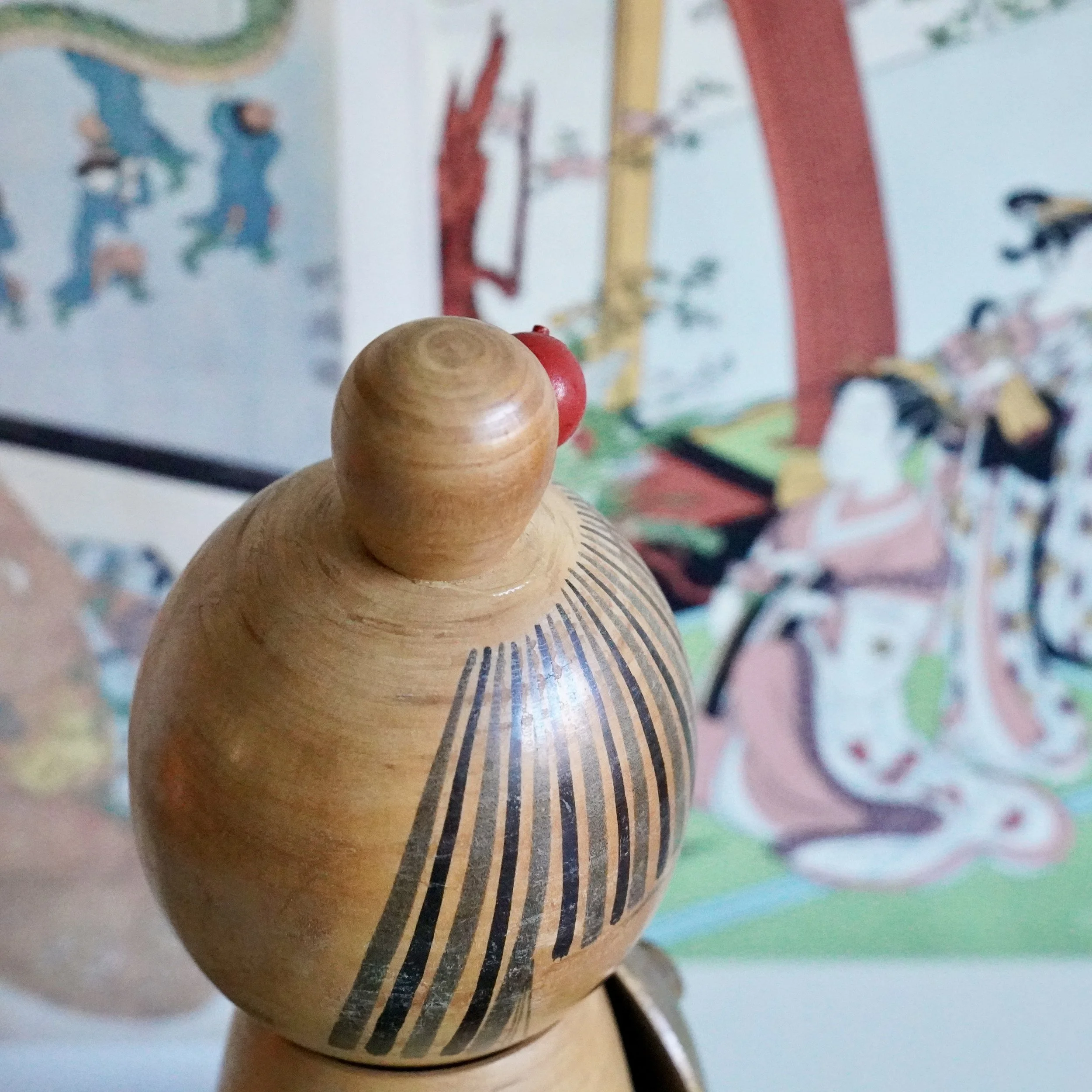 Side profile of Sato Suigai kokeshi showing head striping and wooden kasa hat join