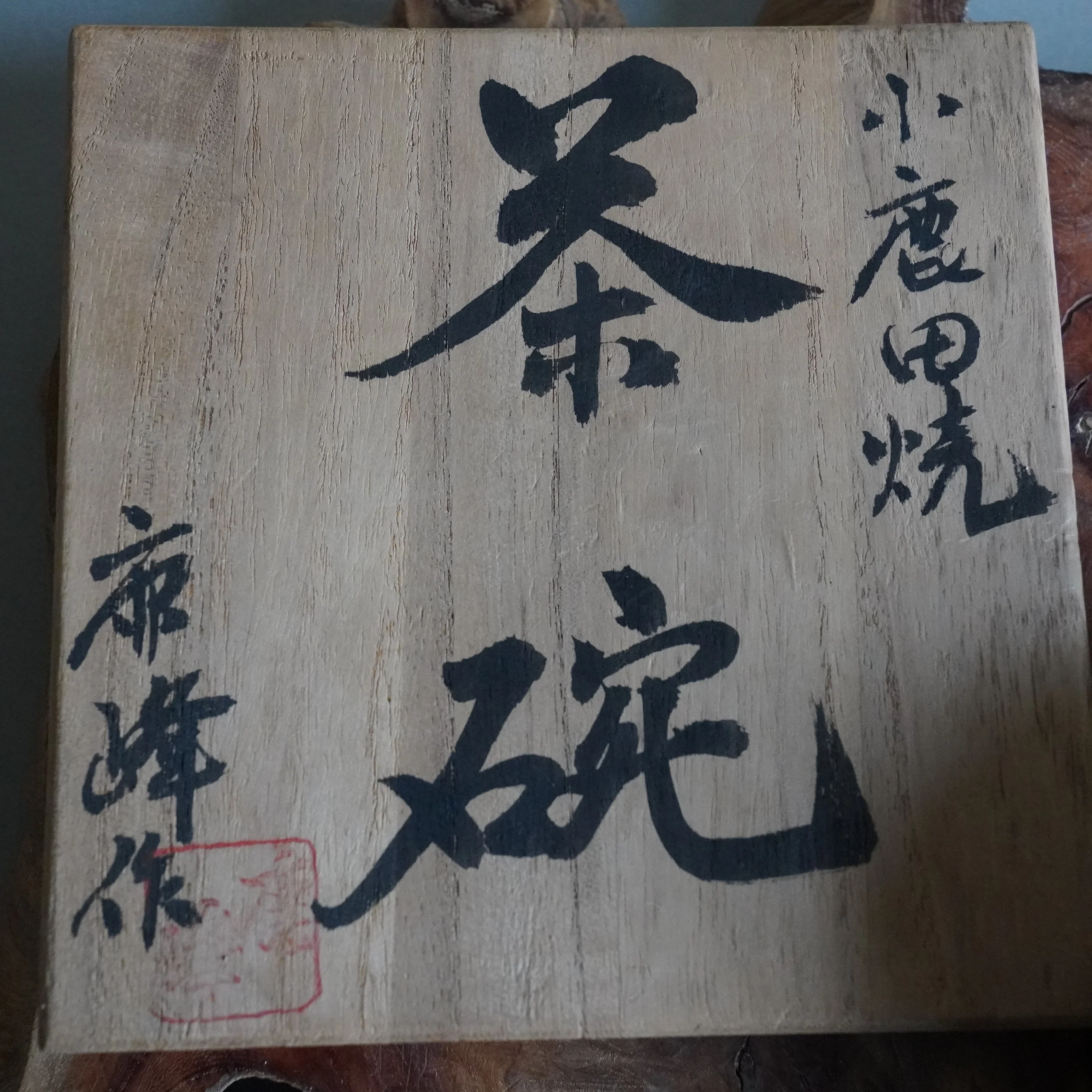 Front view of a light wooden box with visible wood grain. Black Japanese calligraphy reads "Onta-yaki Chawan" and "Rokuhō Saku", with a red seal at the bottom left.