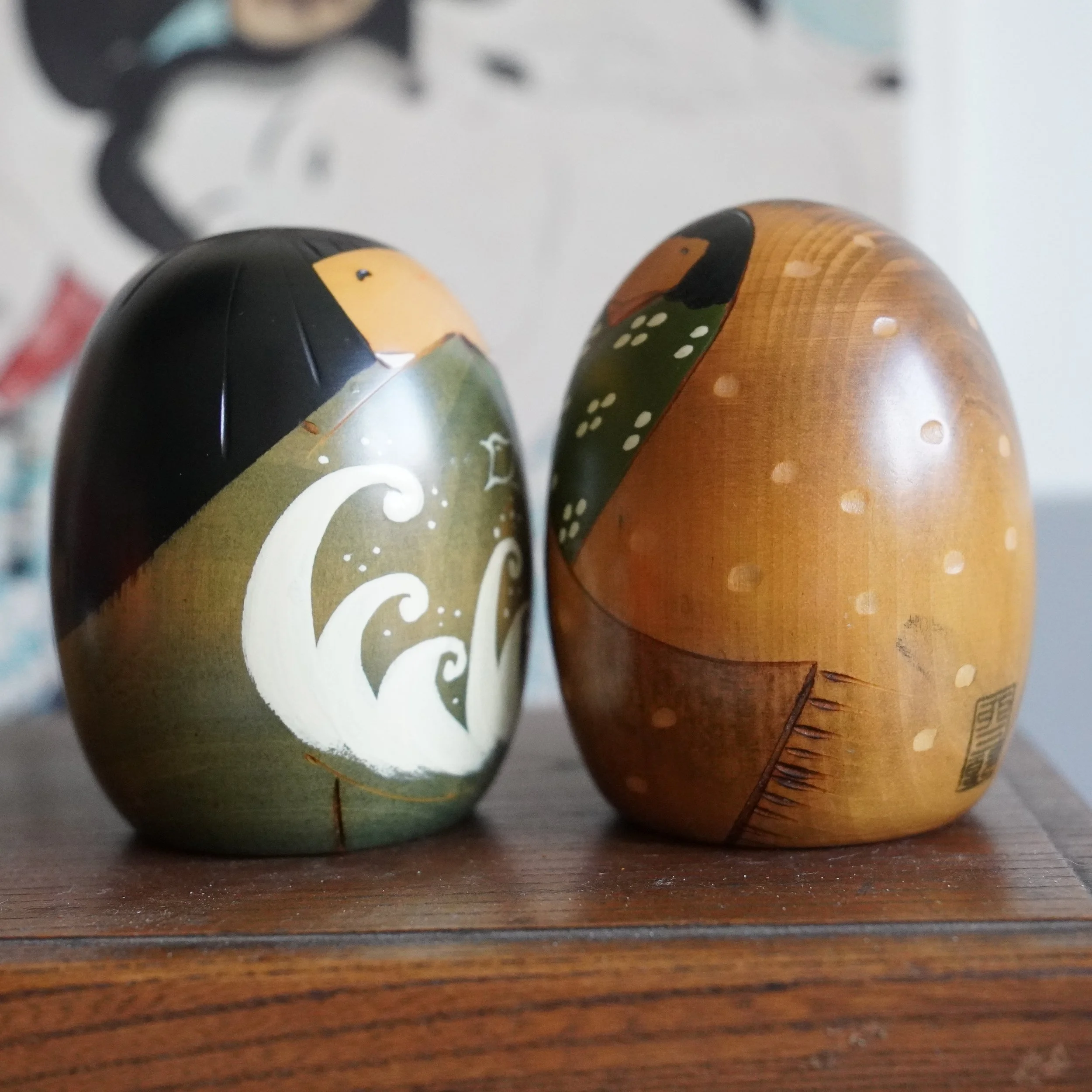 Close up front view of vintage Usaburo kokeshi pair, hand painted faces, summer and winter motifs, Showa period