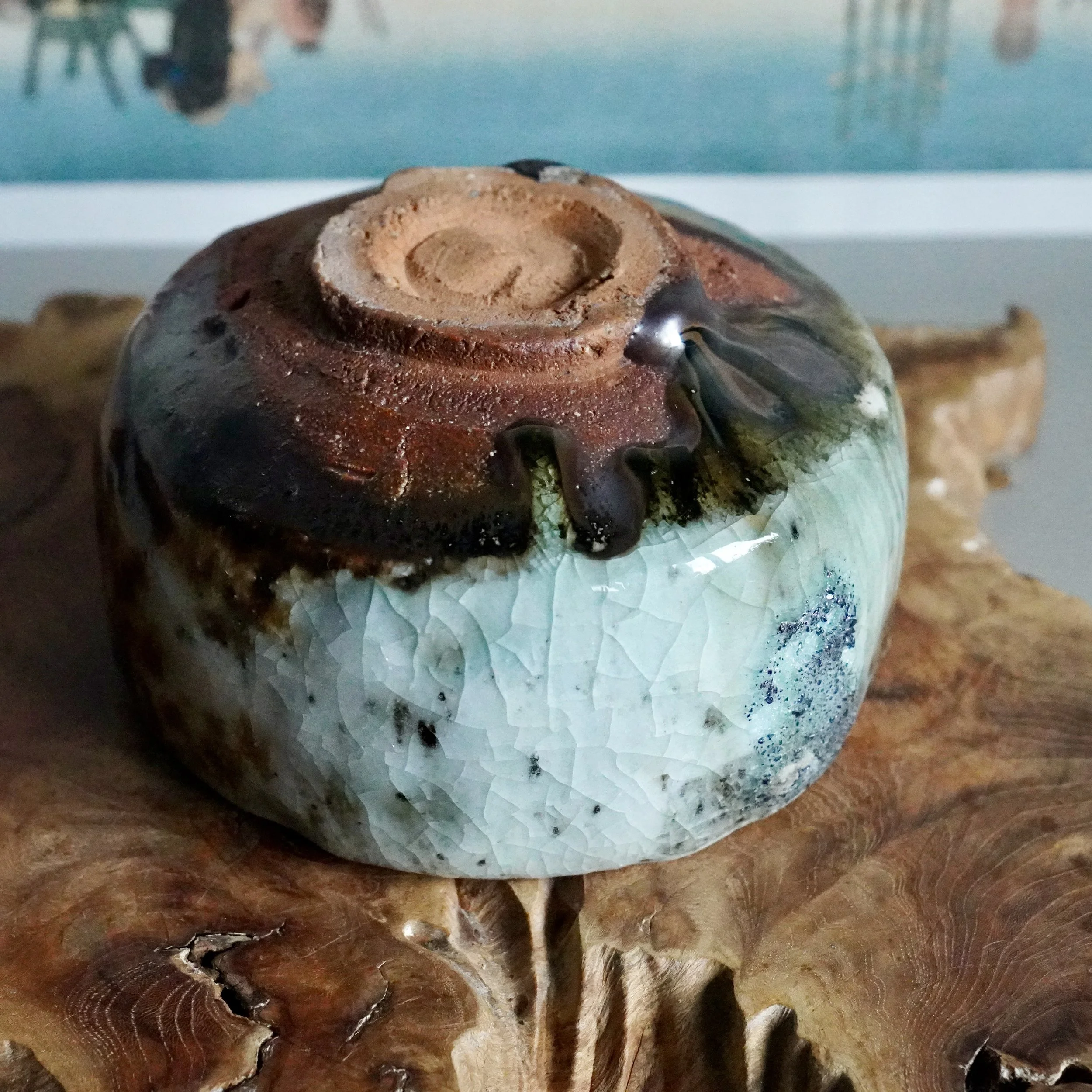 Deguchi Eiji chawan featuring a crackled turquoise glaze transitioning to rustic brown and black, with an unglazed footring, on wood.