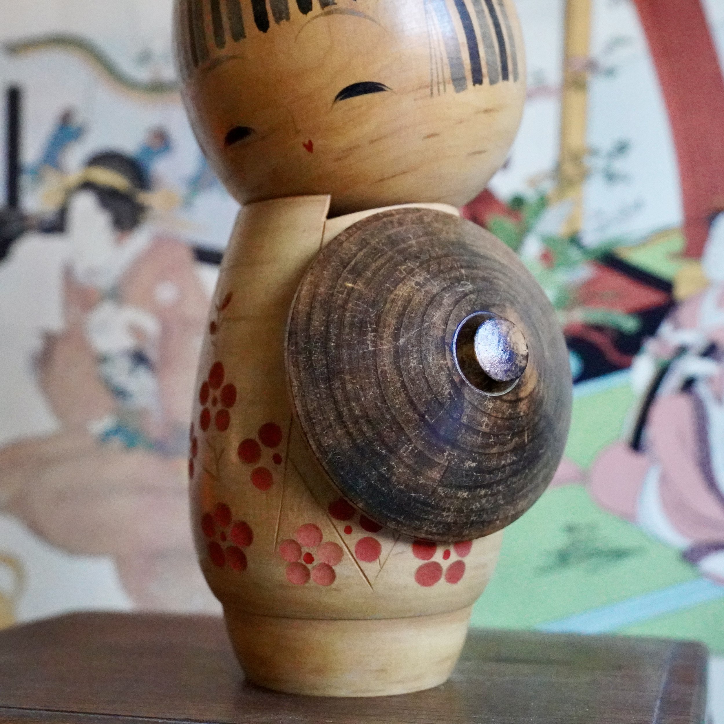Sato Suigai kokeshi side view, wooden kasa travel hat held against the body, oshinobi dōchū style