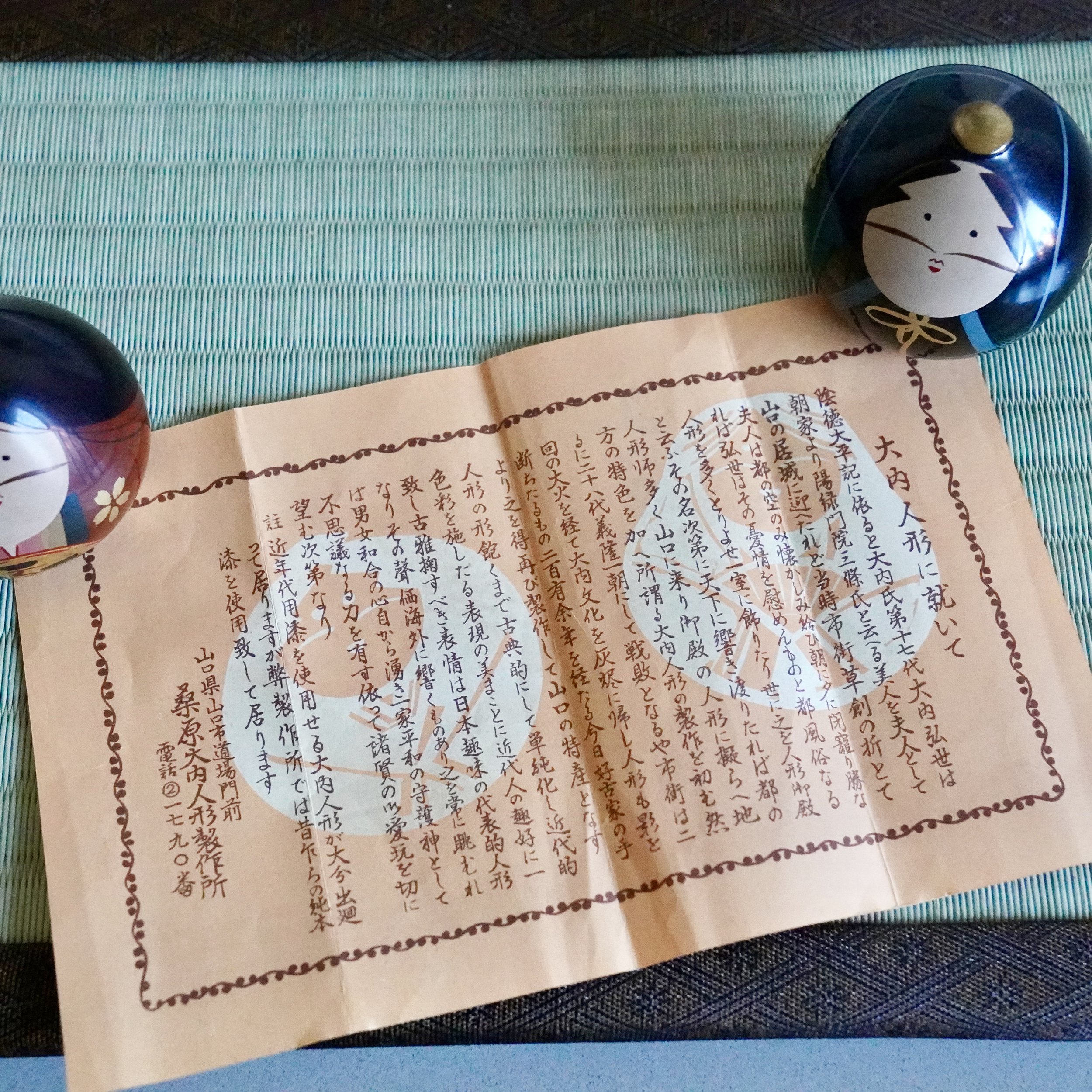 Ouchi-nuri groom hina doll resting on original workshop certificate leaflet, Shōwa period