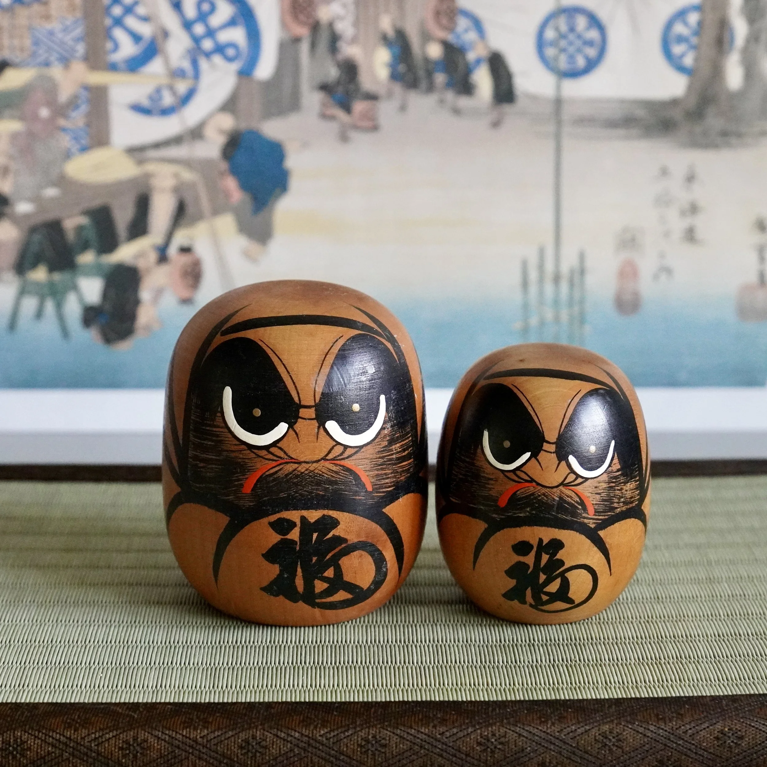Close up of a vintage wooden daruma pair, bold black eyes and fuku kanji, Showa period folk art.
