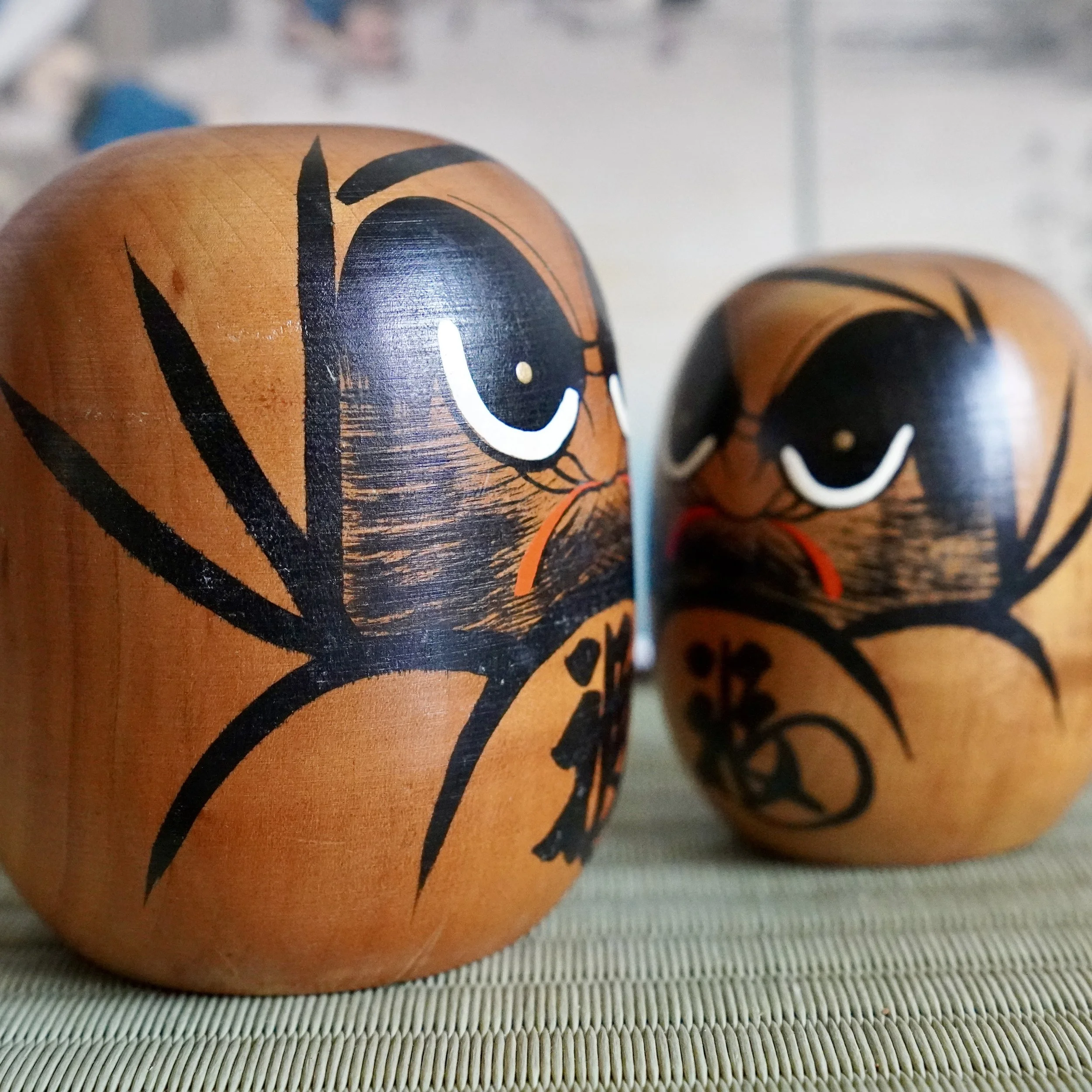 Close up of a hand painted daruma face with black bamboo motif brushstroke, vintage Japanese wood craft.