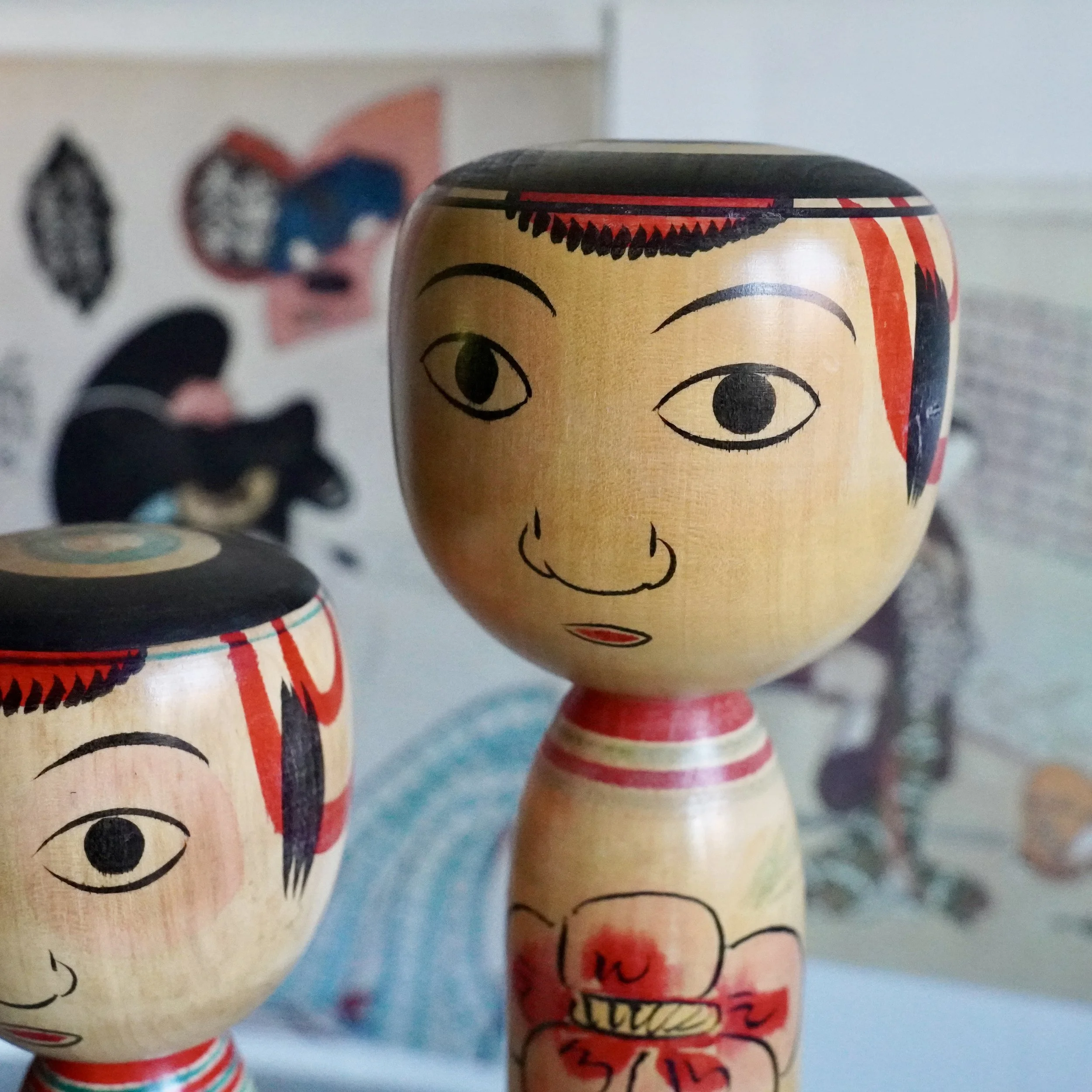 Close up of two Nakanosawa Takobozu kokeshi heads, painted red rimmed eyes and hairline, signed Saito Tokuju kokeshi