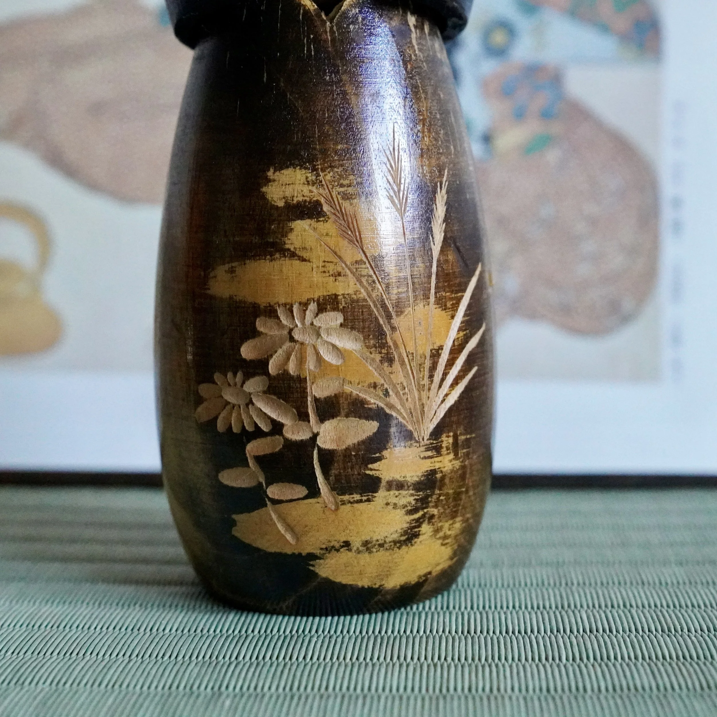 Carved autumn grasses detail on lacquered kokeshi surface