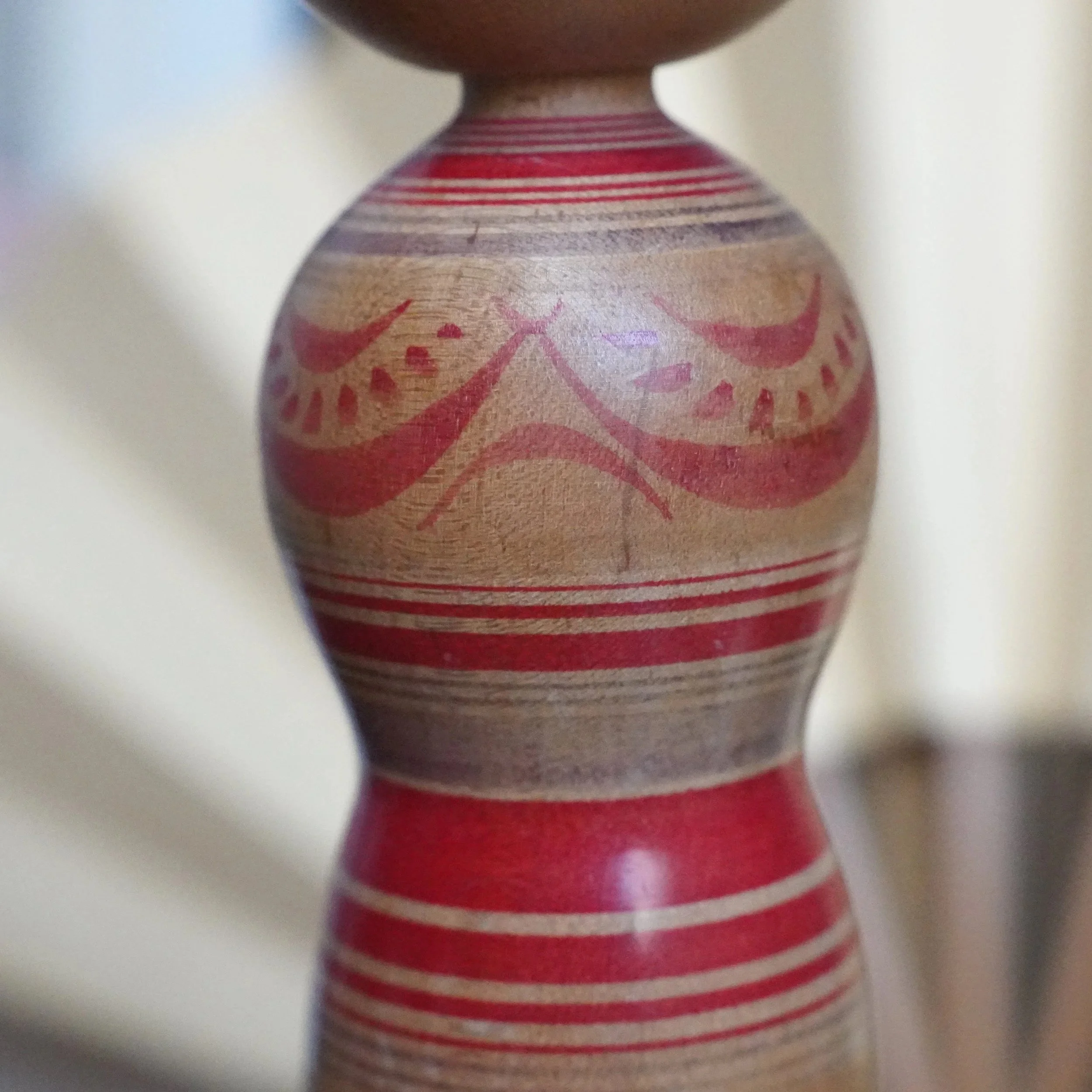 Tsugaru kokeshi doll's hourglass body. Red peony designs on light wood, accented by red horizontal stripes. Signed by Sasamori Junichi.