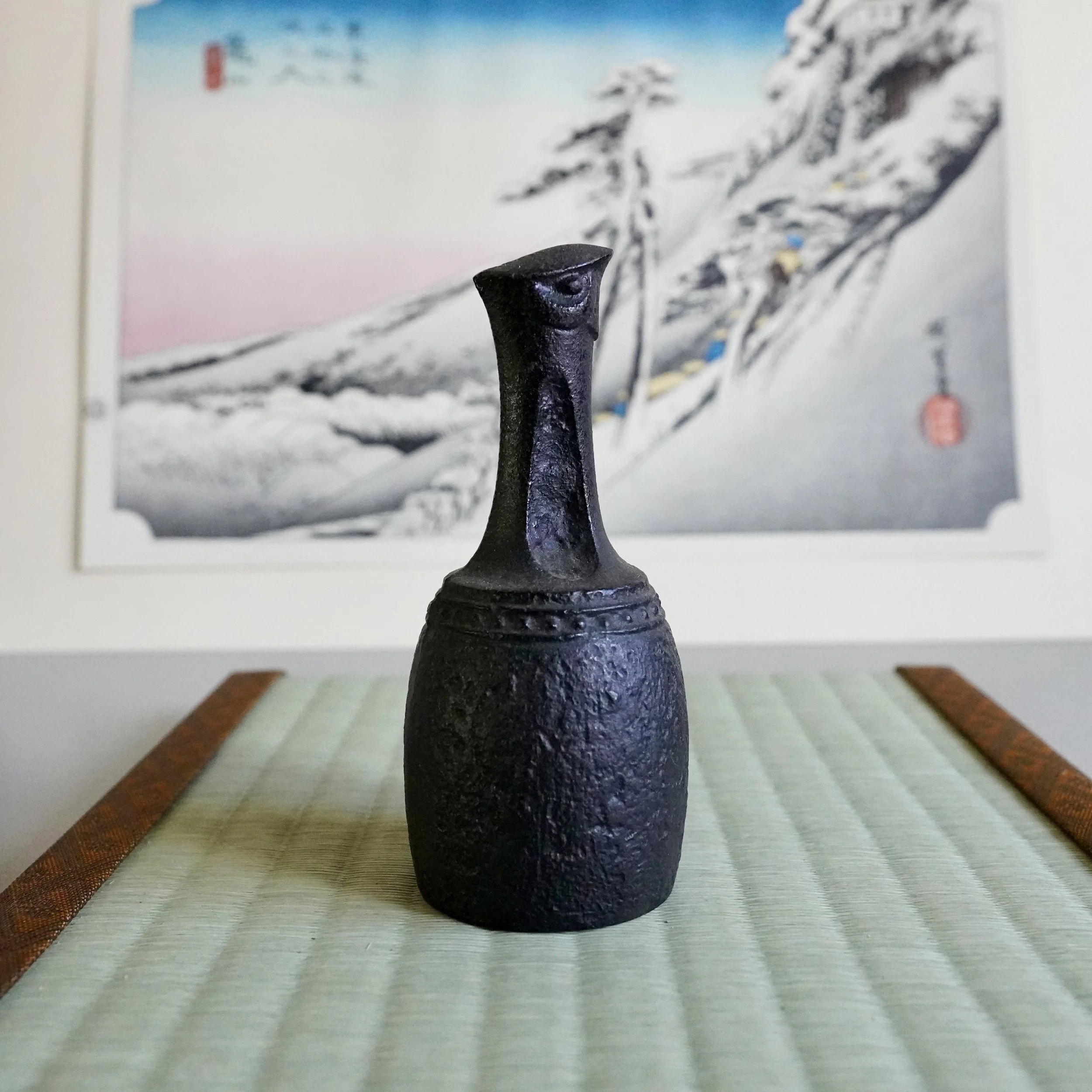 Nanbu Tekki cast iron yamadori bird bell Iwate Prefecture hand-cast aged patina displayed on tatami mat with ukiyoe print in background, Shōwa period 1970 Japan