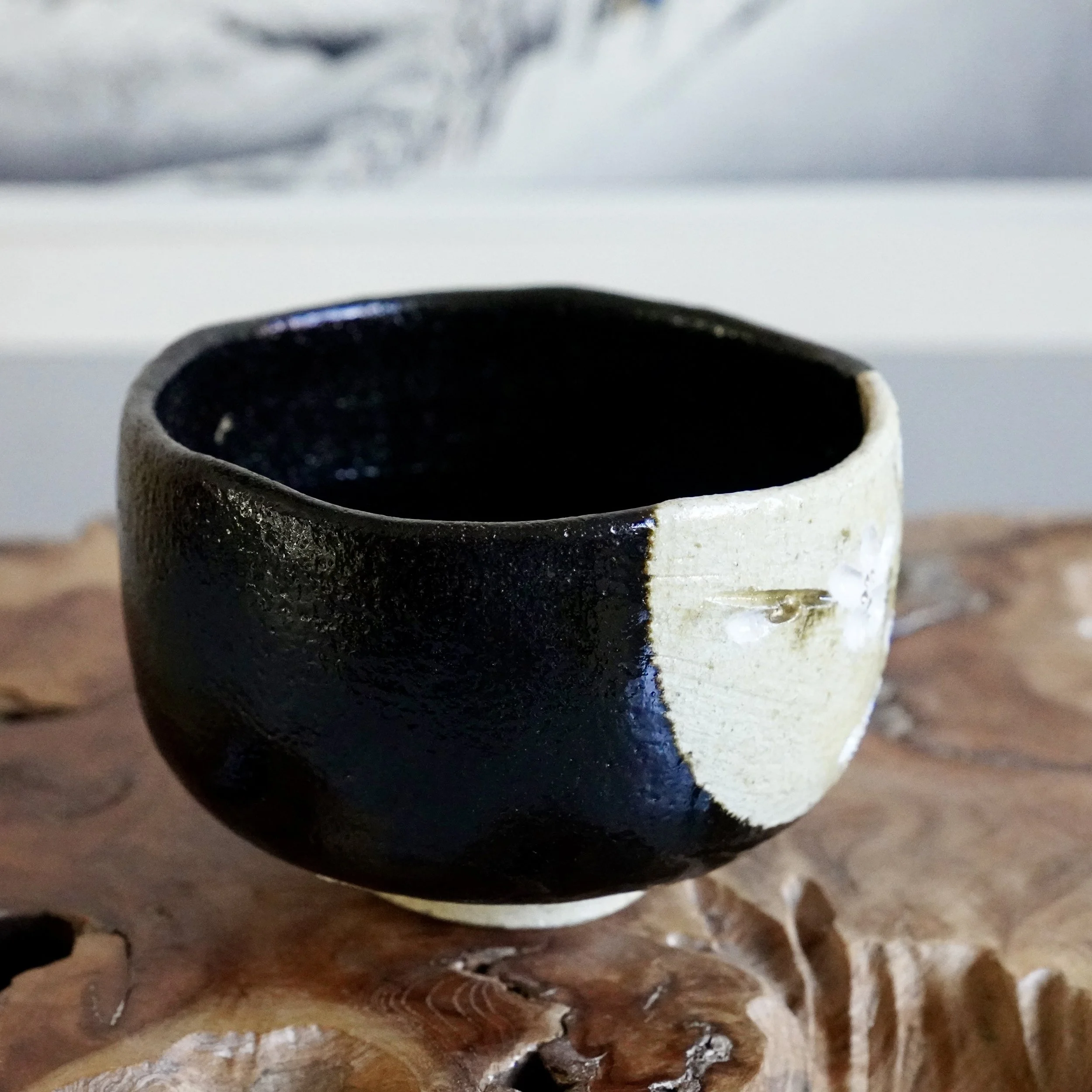 Angled view of black glazed chawan with cherry blossom decoration