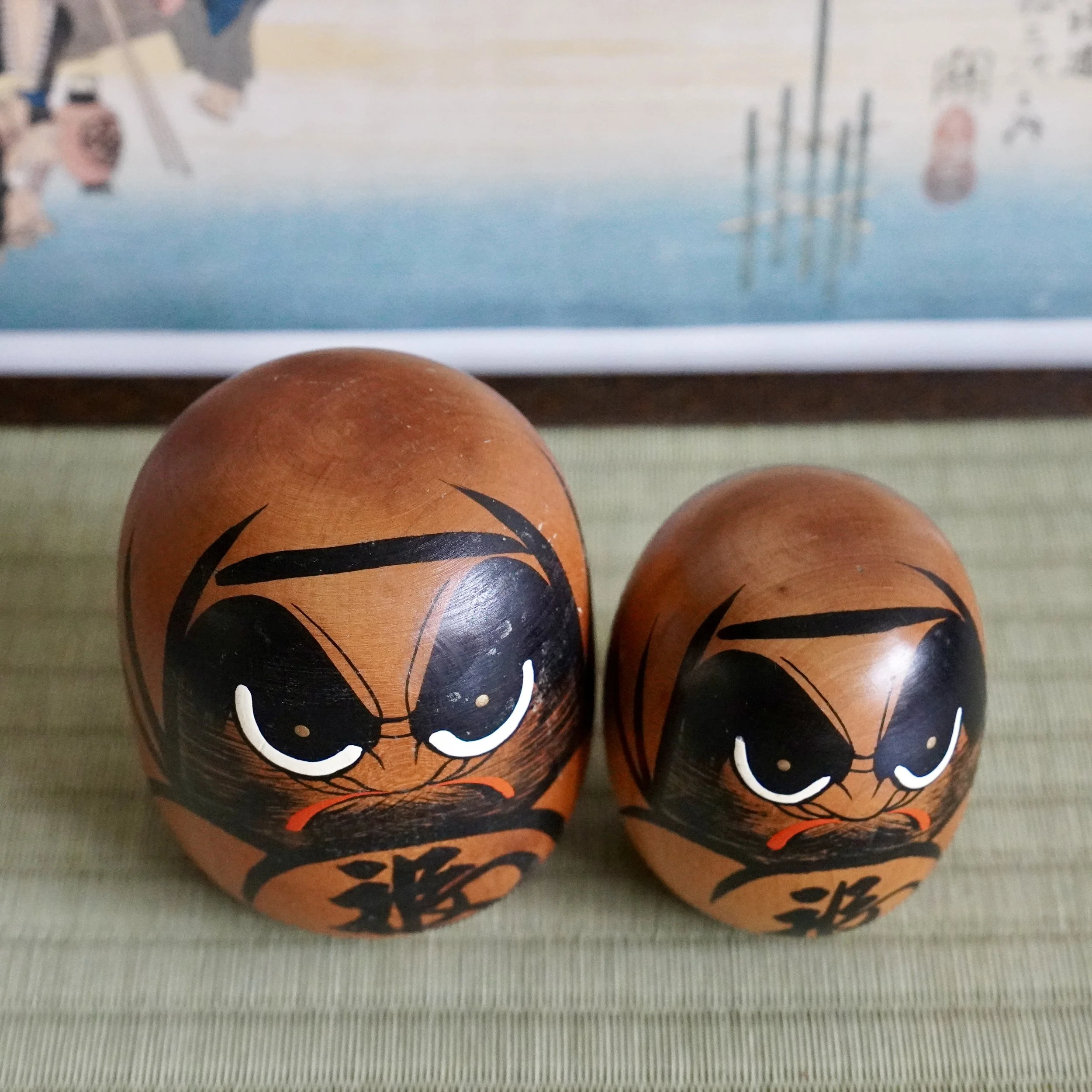 Vintage wooden daruma pair side by side, hand painted faces, Japanese Showa period folk craft.