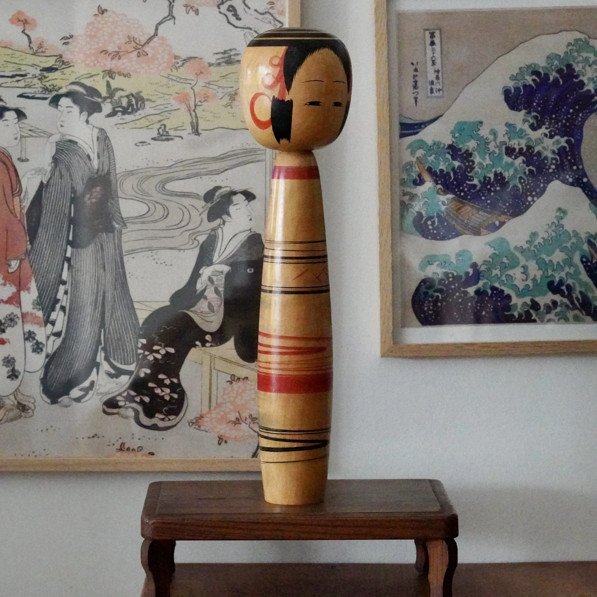 Tsuchiyu kokeshi doll by Abe Kazue, three-quarter view on wood stand