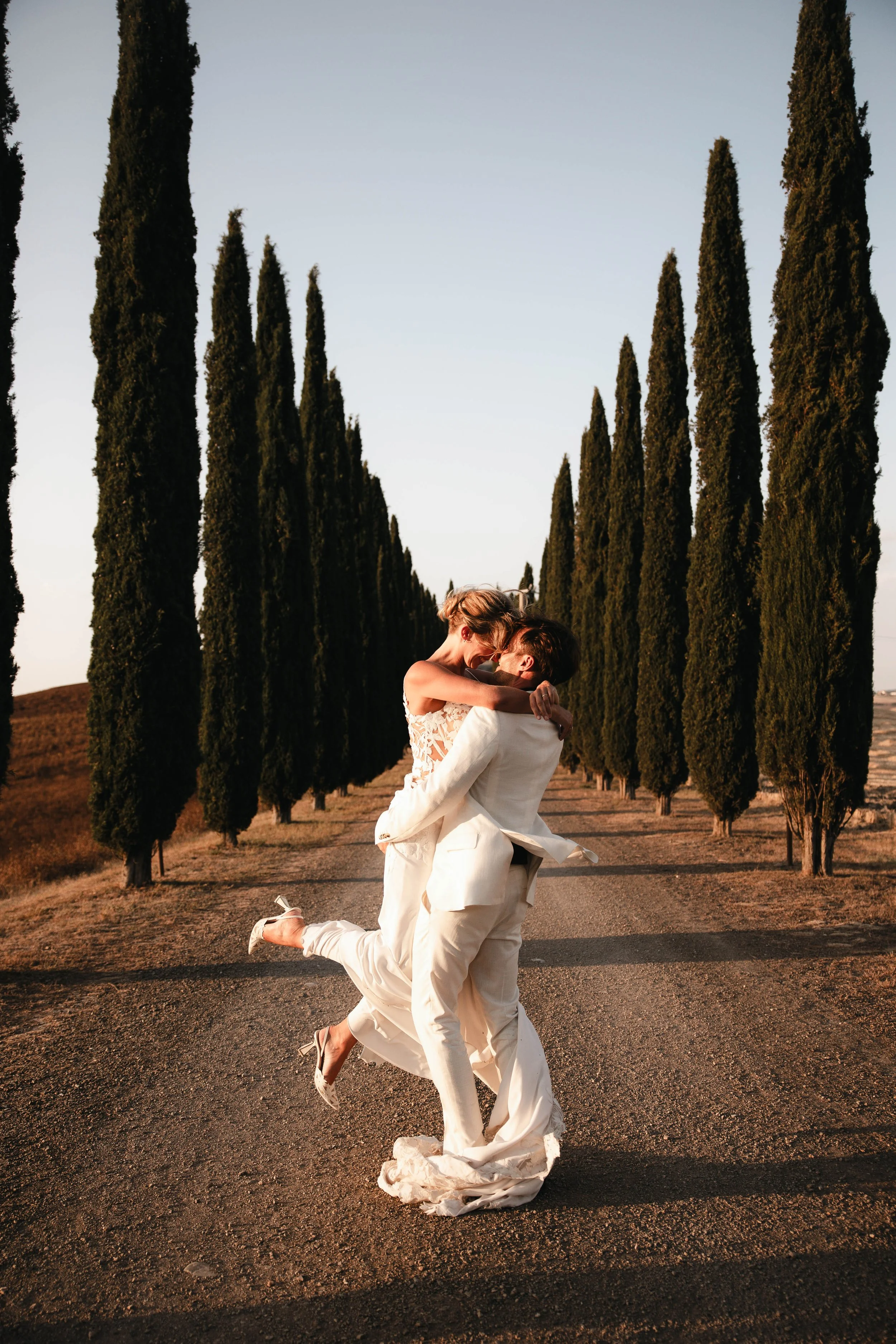Couple kiss wedding in Val D'orcia, cypresses and sunset atmosphere. Villa Apparita.