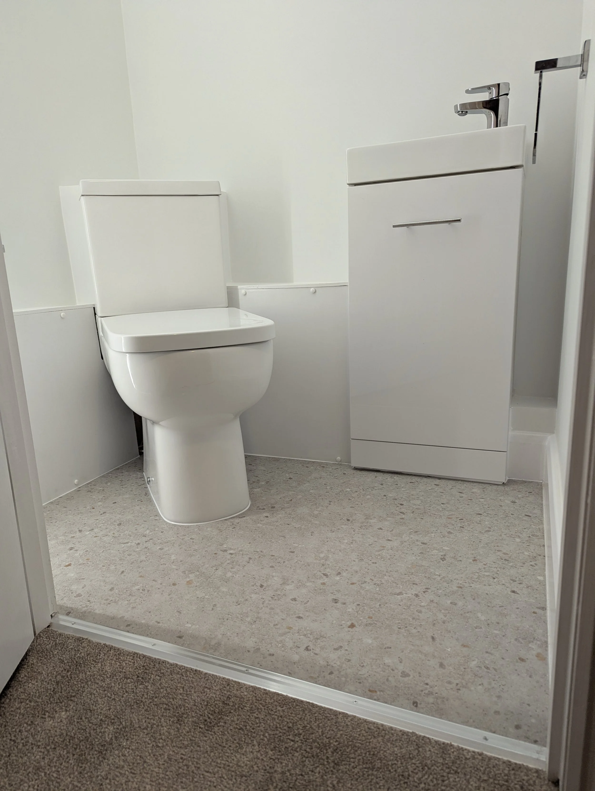 Small bathroom with a white toilet and a white sink cabinet.