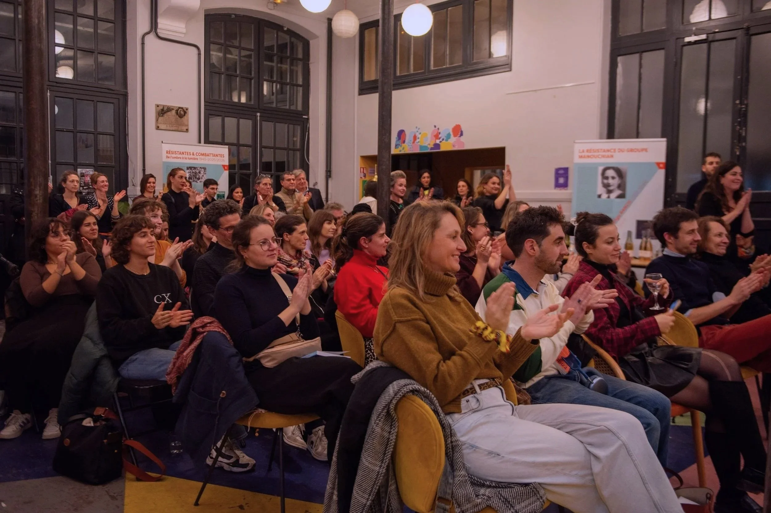 Audience de personnes applaudissant dans une salle lors d'un événement.