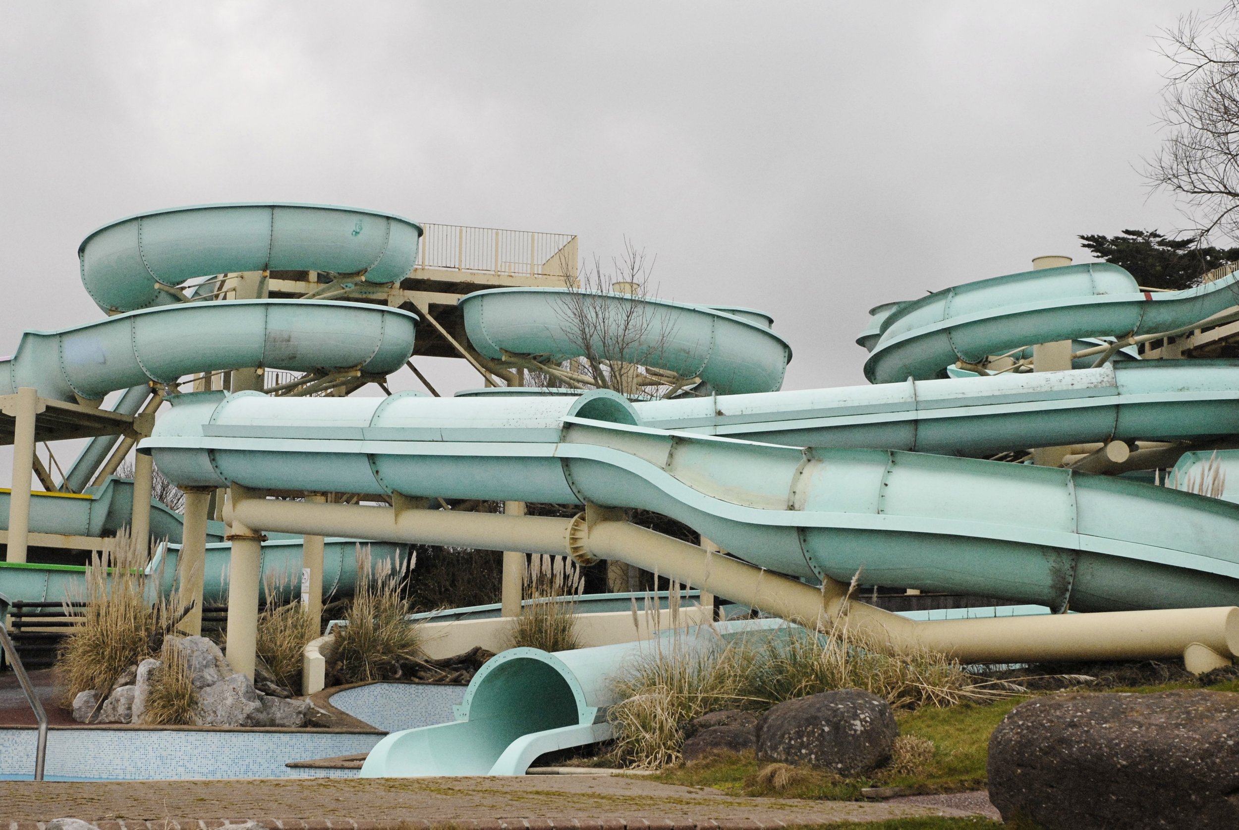 Empty water slides at an outdoor water park, against a cloudy sky.