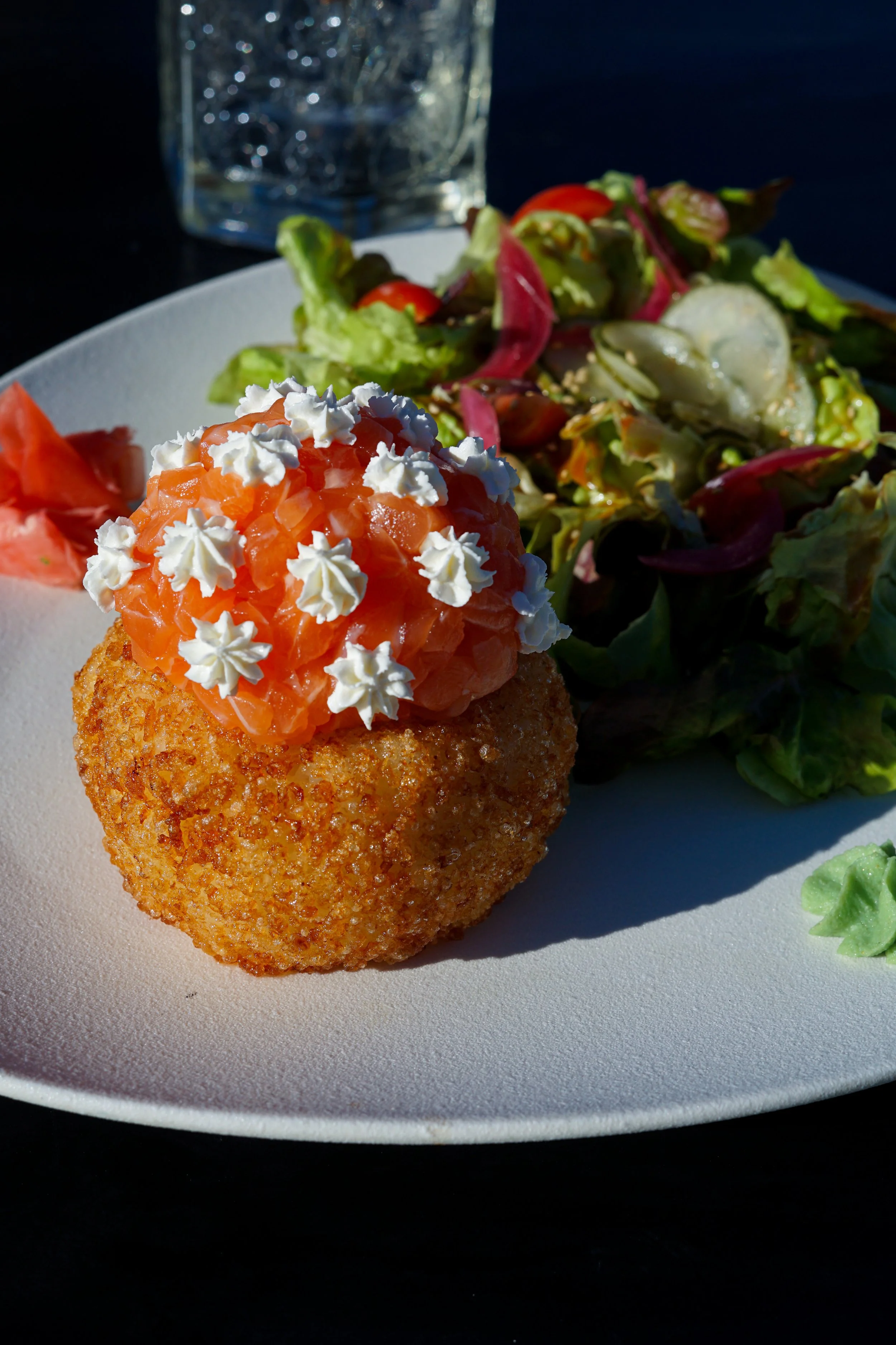 Croquette avec saumon fumé et crème, accompagnée d'une salade verte dans une assiette blanche.