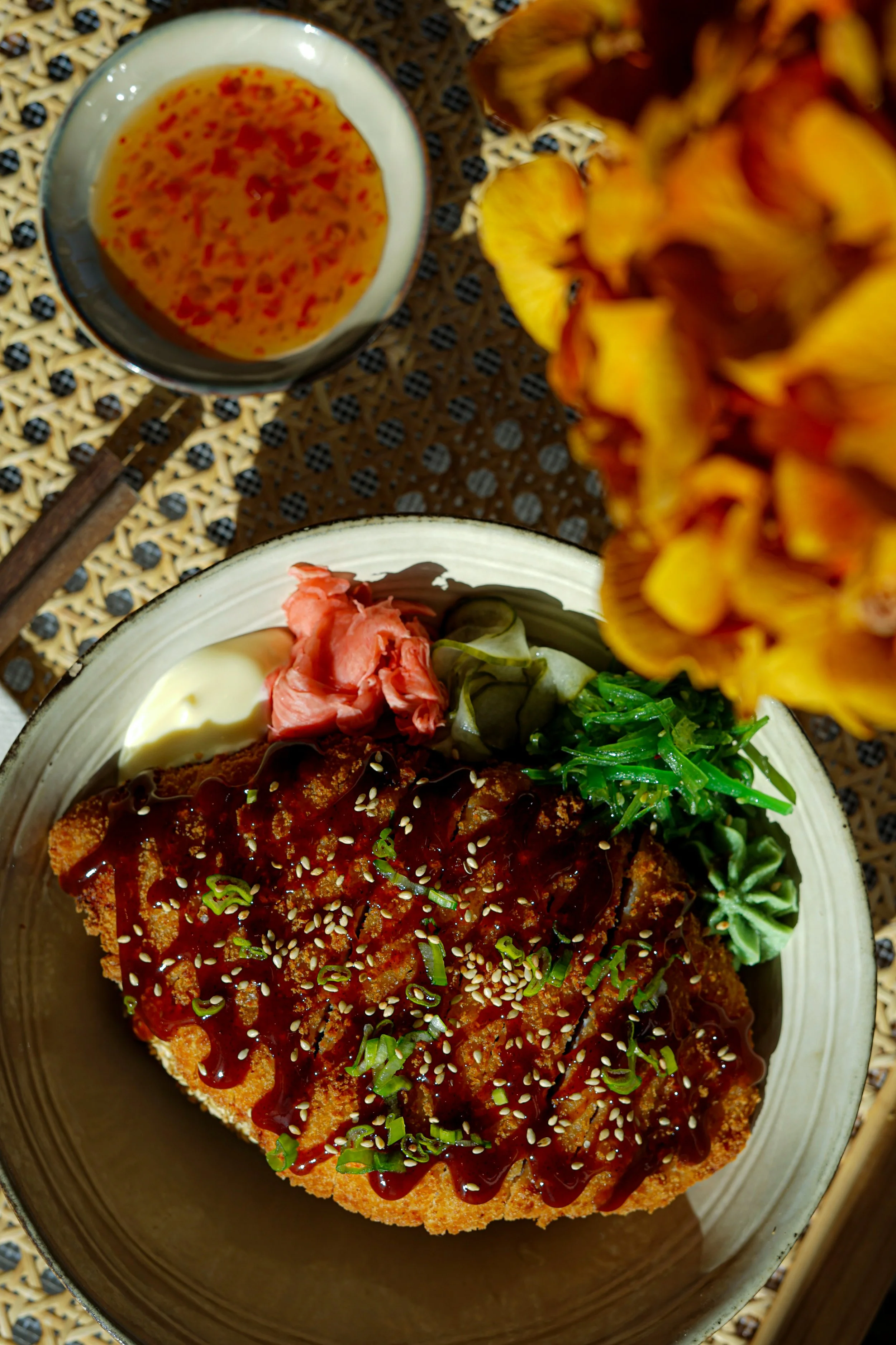 Assiette de nourriture asiatique avec du riz, un filet de poisson en sauce, des légumes verts, du gingembre mariné, un œuf à la crème, des tranches de fruit et une boisson.