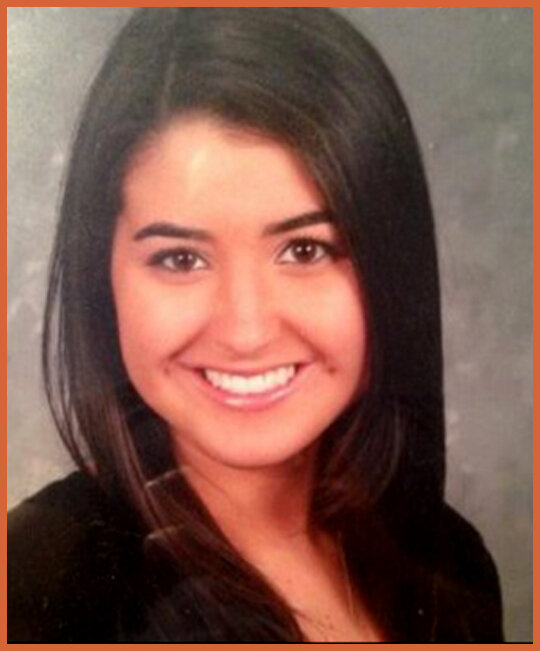 A young woman with straight dark hair smiling at the camera, wearing a black top.