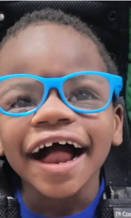 A smiling young boy with glasses and missing front teeth.