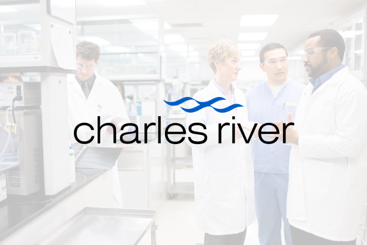 Four scientists in lab coats engaged in discussion in a laboratory setting with equipment in the background, overlaid with the Charles River logo.