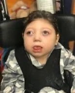 Young girl with dark hair, sitting in a car seat, making a silly face with her tongue out.